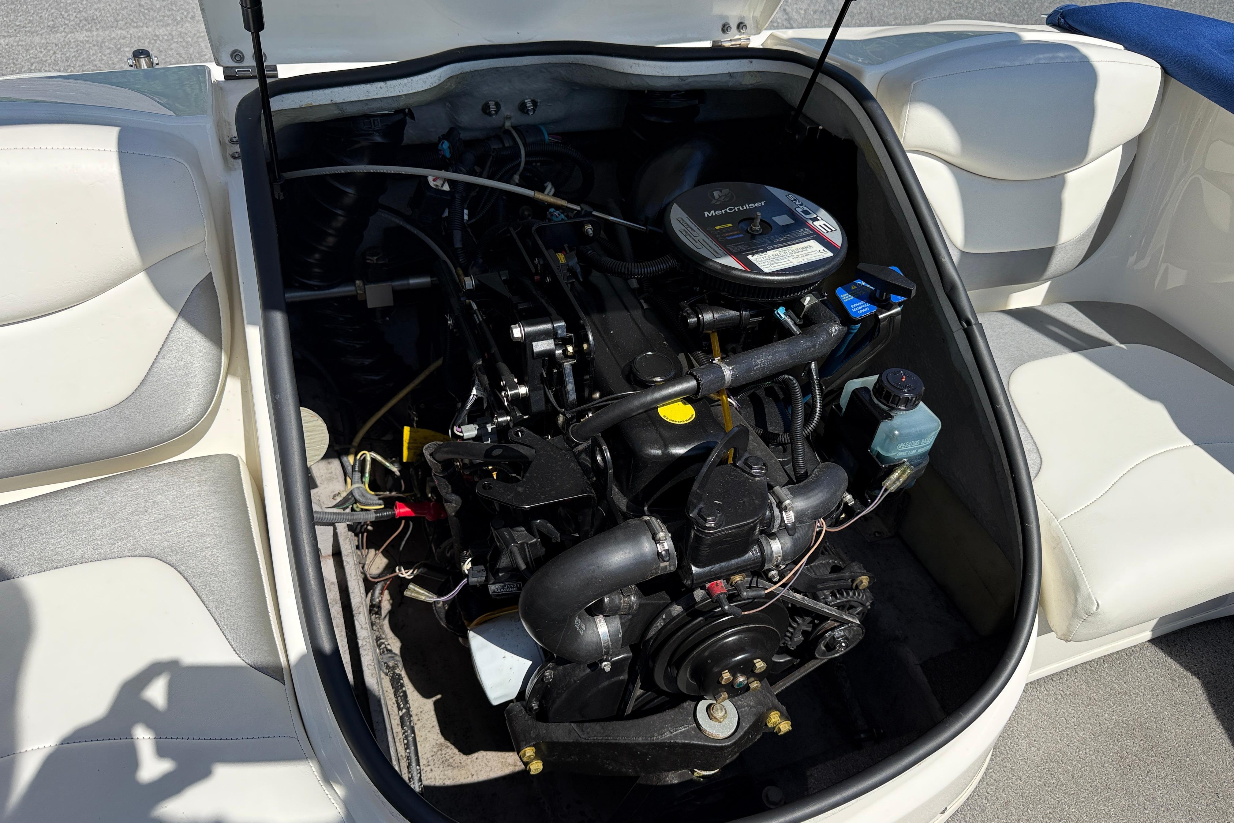 2009 Bayliner 175 boat engine compartment with MerCruiser engine, surrounded by white seating.