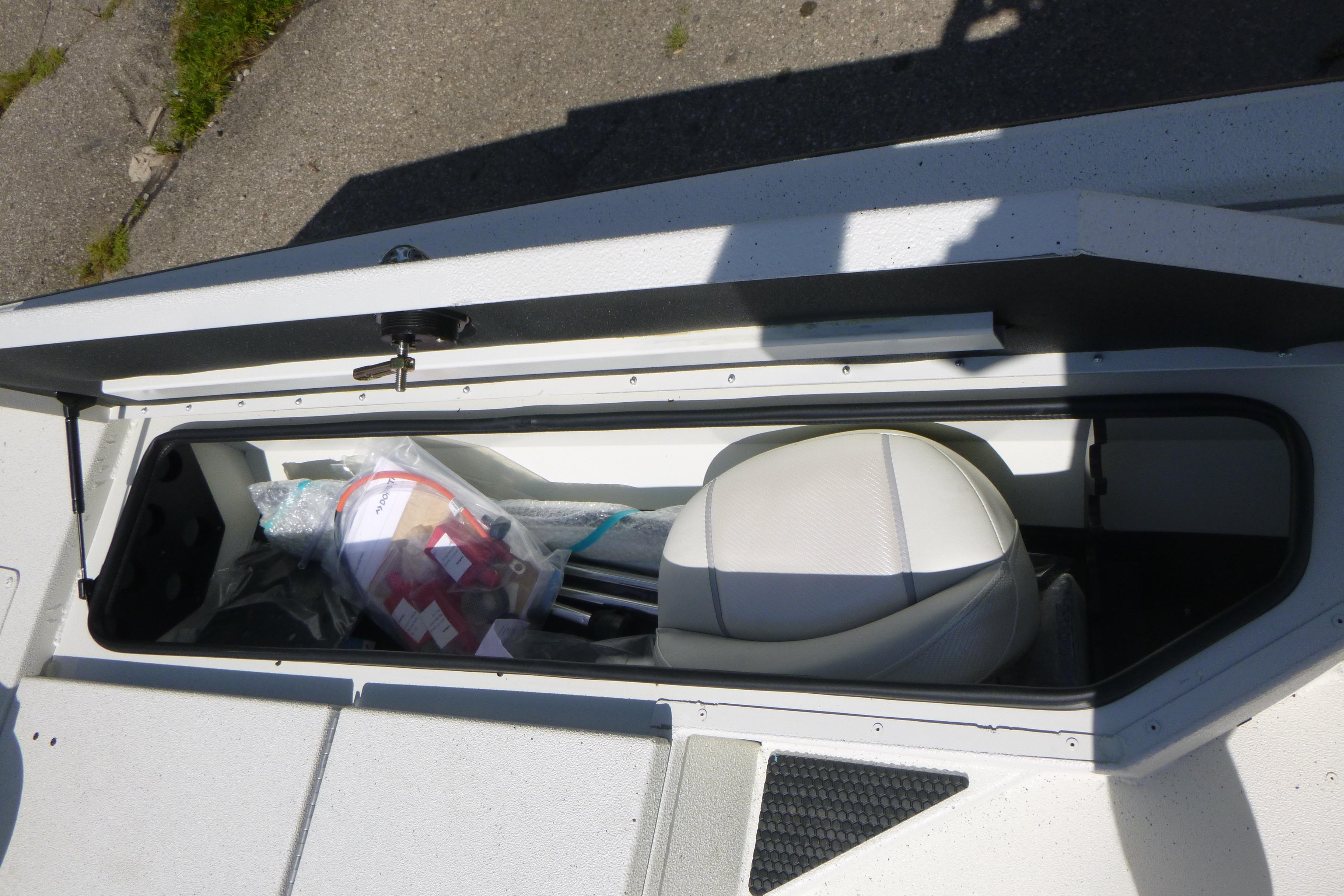 Storage compartment in a 2025 Ranger RB210 boat, containing various items and a seat.