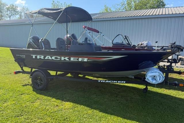 2026 Tracker Pro Guide V-16 SC boat on trailer, parked on grass near a building.