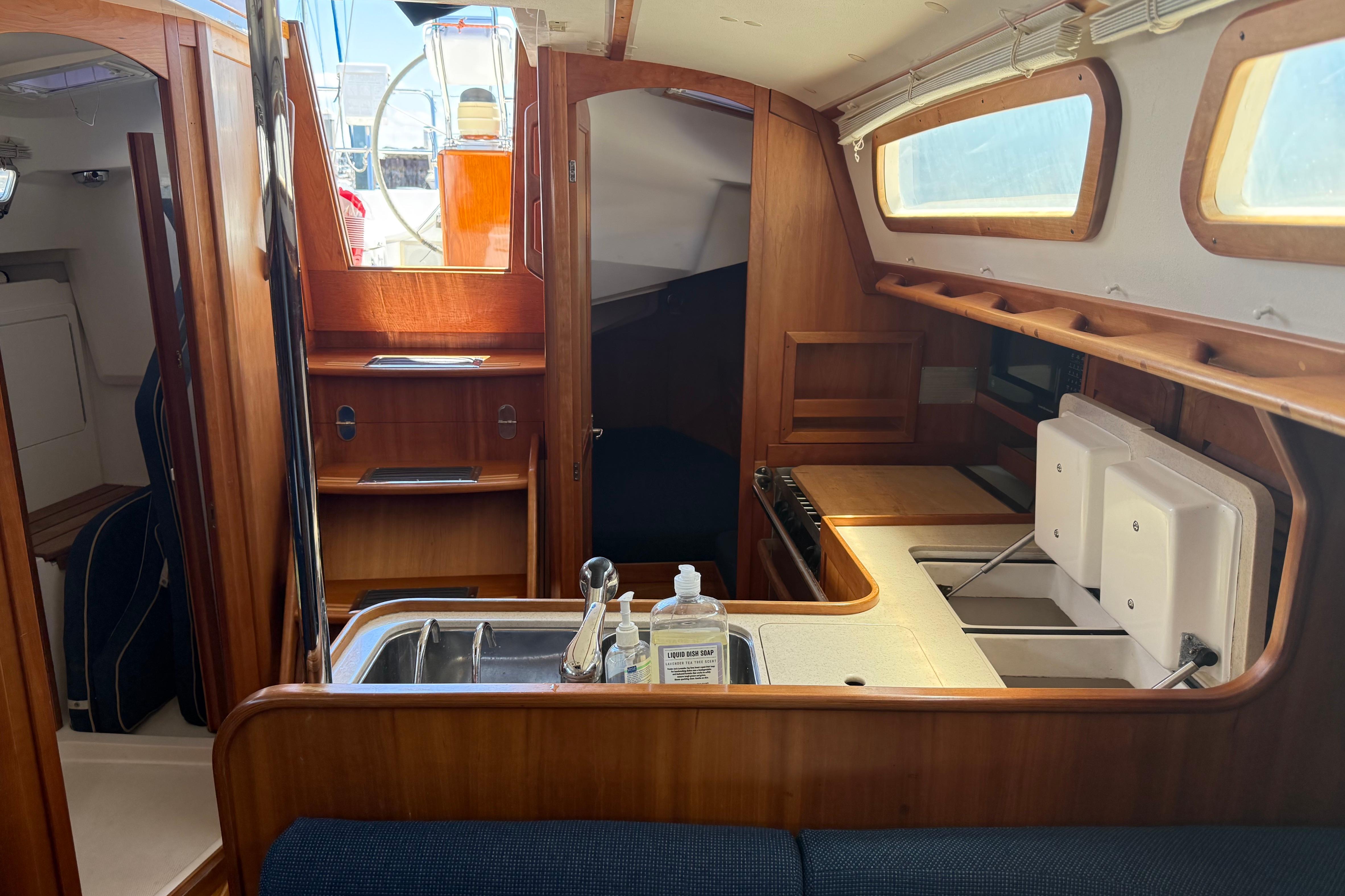 Interior of 2004 Sabre 386 sailboat with wooden cabinetry and compact kitchen area.
