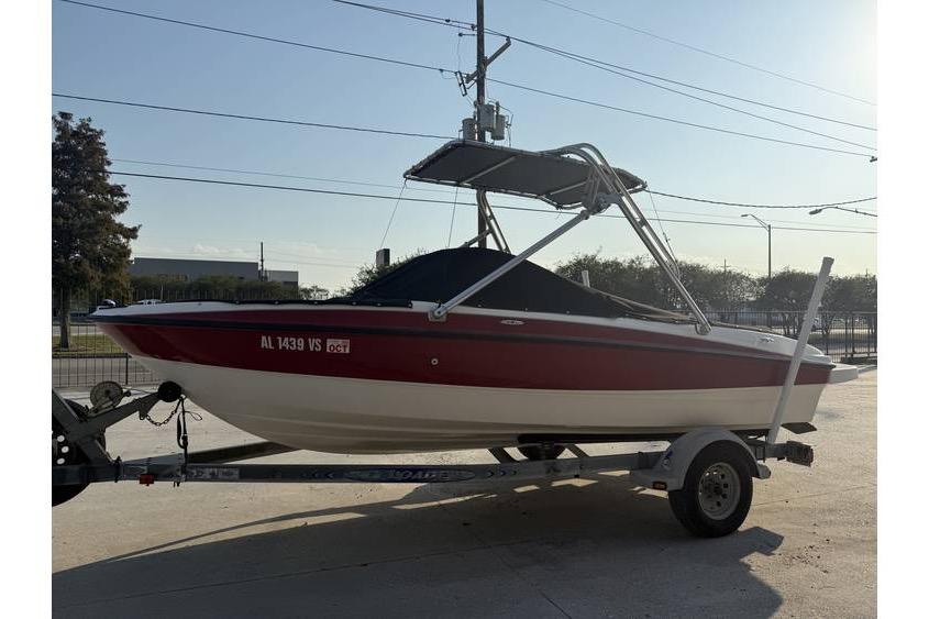 2008 Bayliner 185 Bowrider on trailer, red and white, parked outdoors.