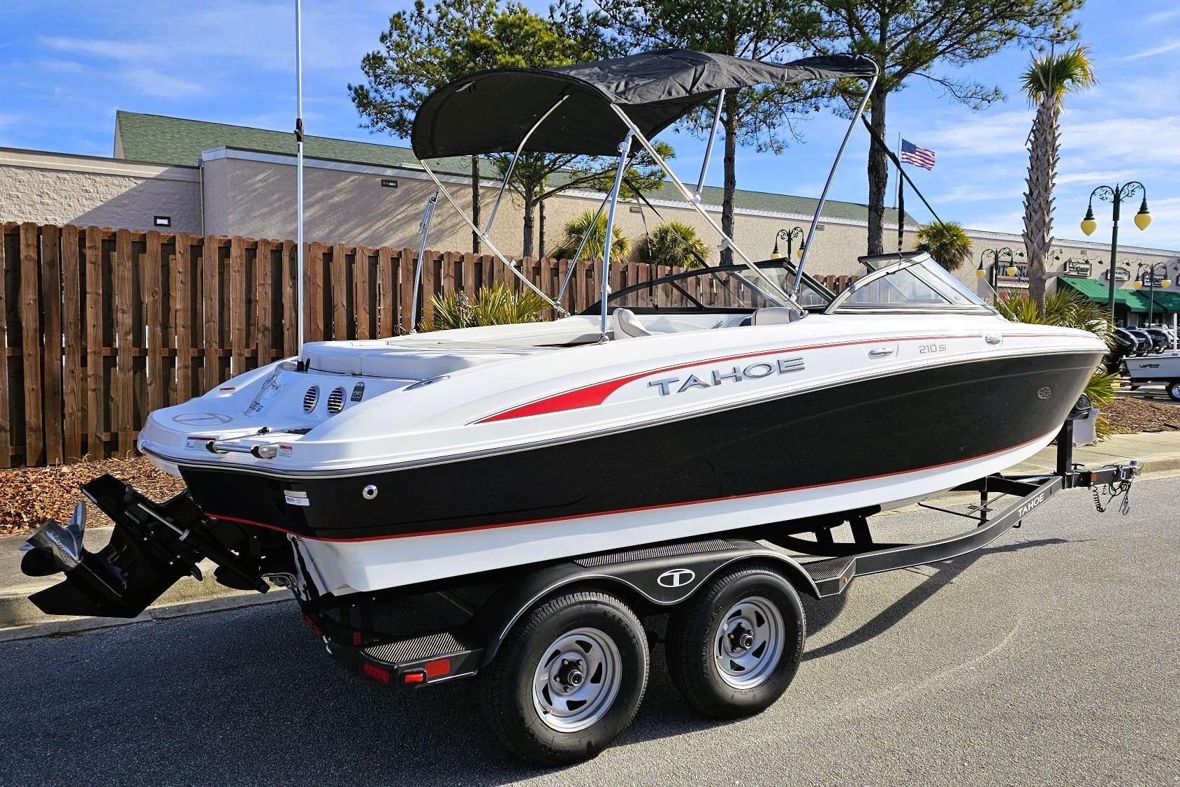 2023 Tahoe 210 Si boat on trailer, black and white design, parked outdoors.