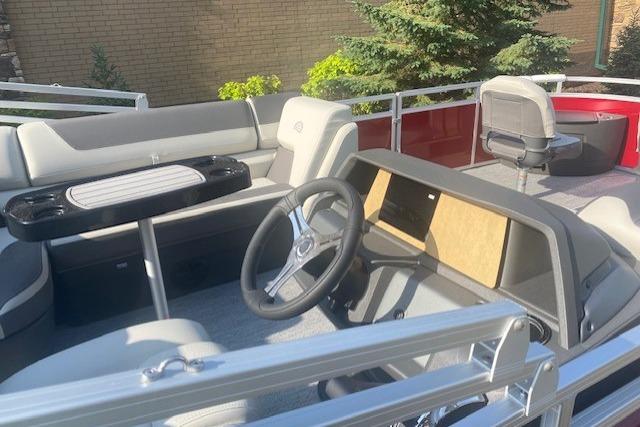 2026 Sun Tracker Fishin' Barge 22 DLX interior with steering wheel and seating.