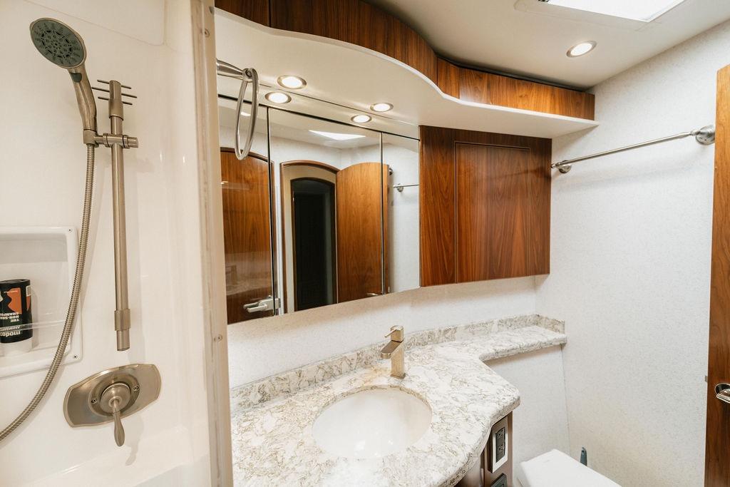 Luxurious bathroom in 2021 Viking 58 Convertible yacht with marble countertop and wooden cabinetry.