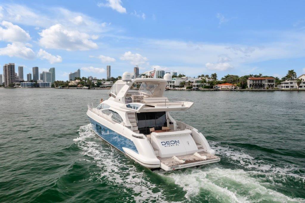 2014 Azimut 64 Flybridge yacht cruising near city skyline and waterfront homes.