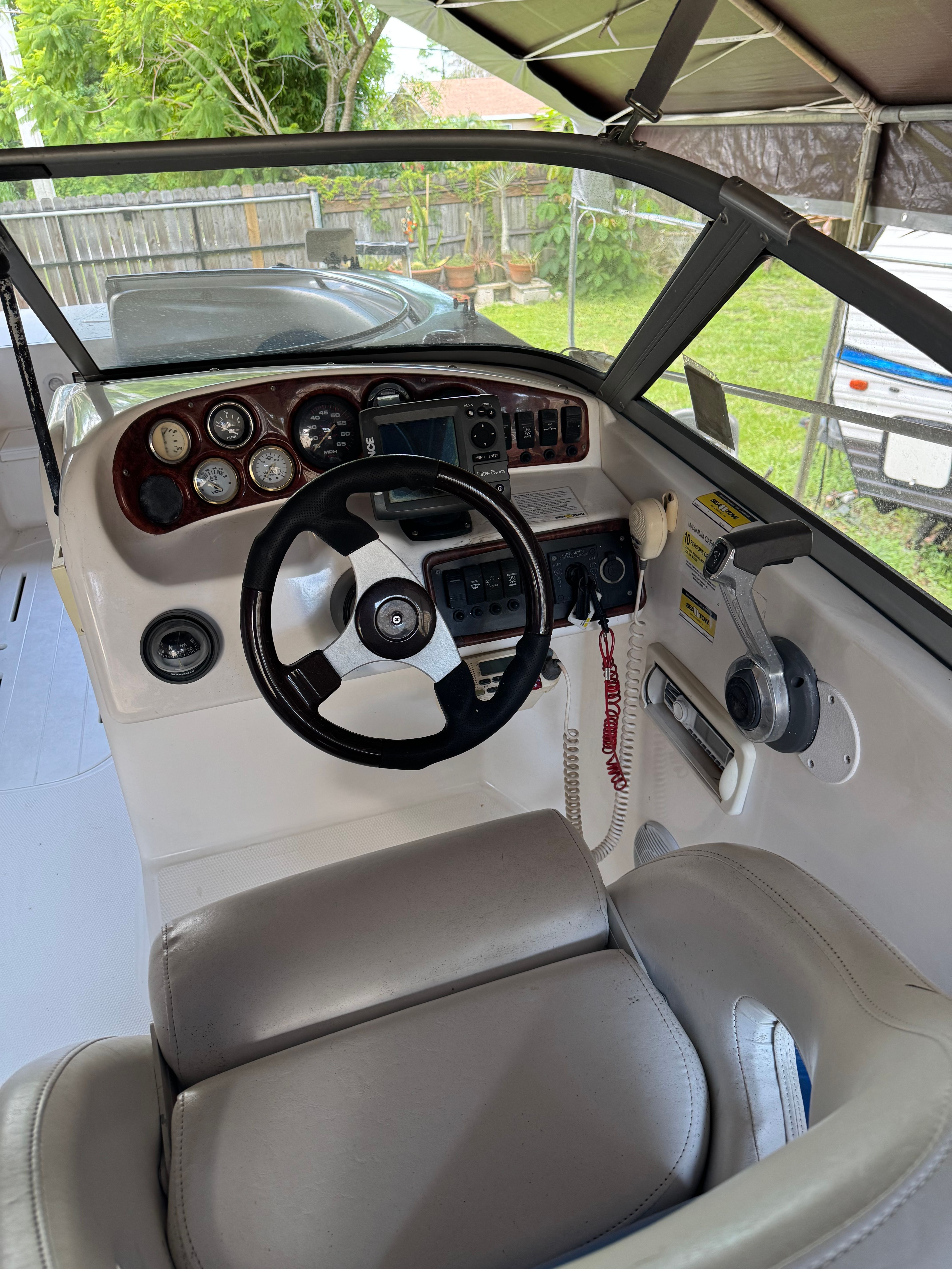 The image shows a boat cockpit with a steering wheel and various instruments.