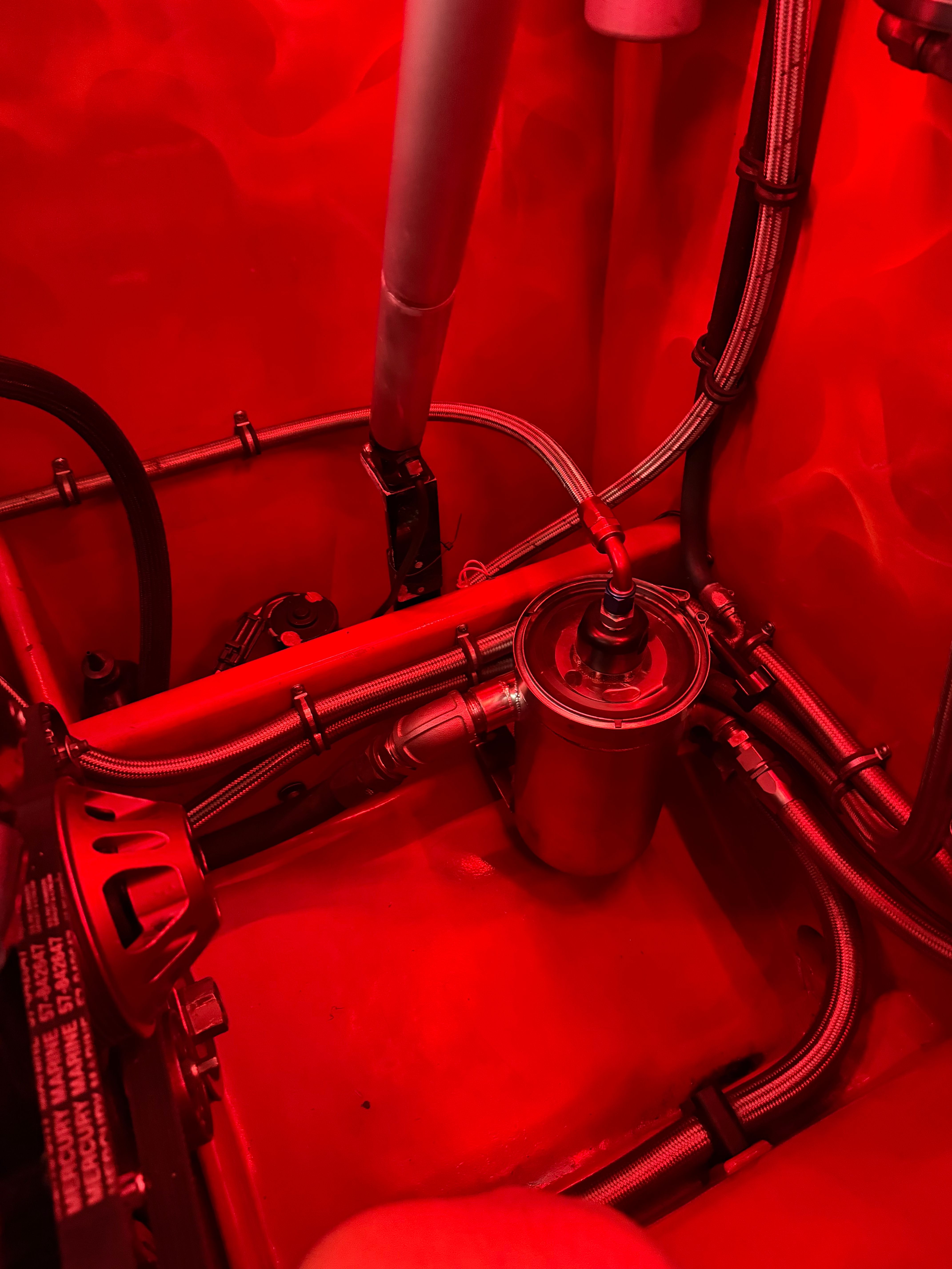 Red lighting reveals the engine compartment of a 2010 MTI CAT with hoses and metal components.
