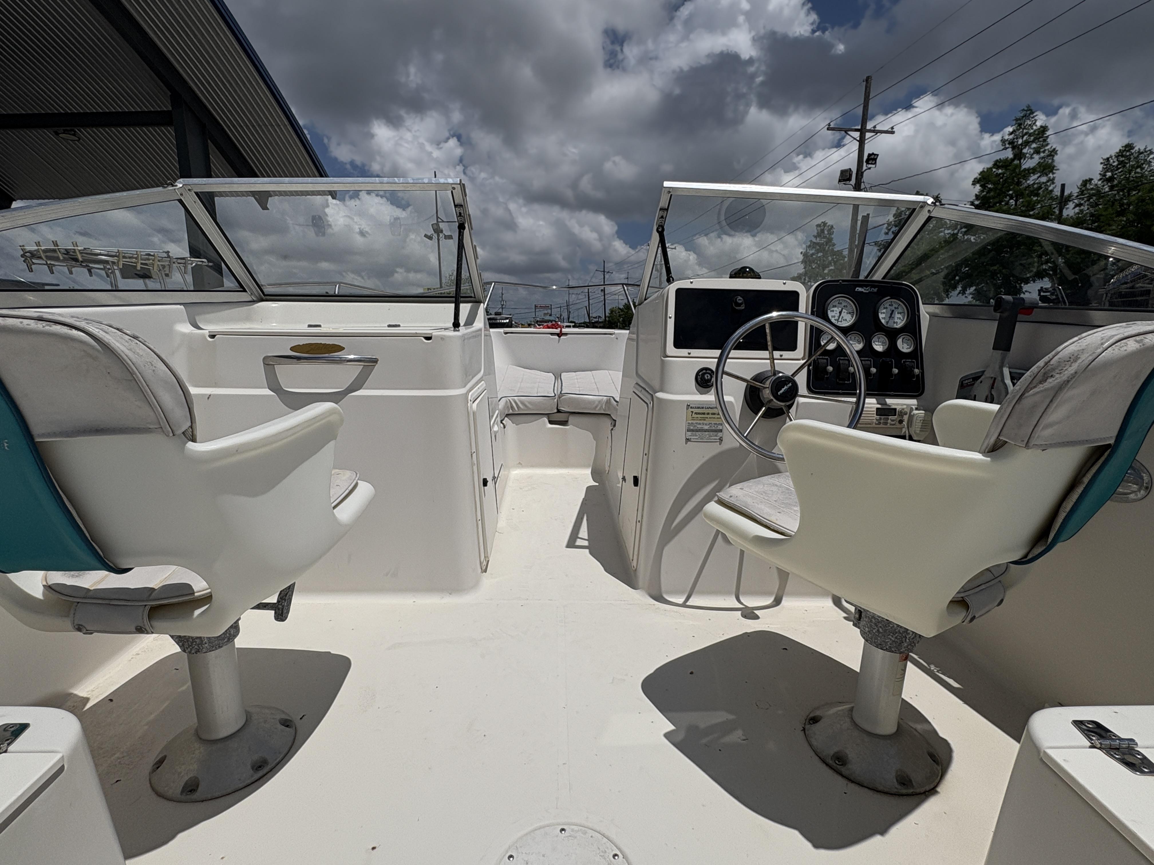 1996 Pro-Line 202 boat interior with dual seats, steering wheel, and dashboard under cloudy sky.