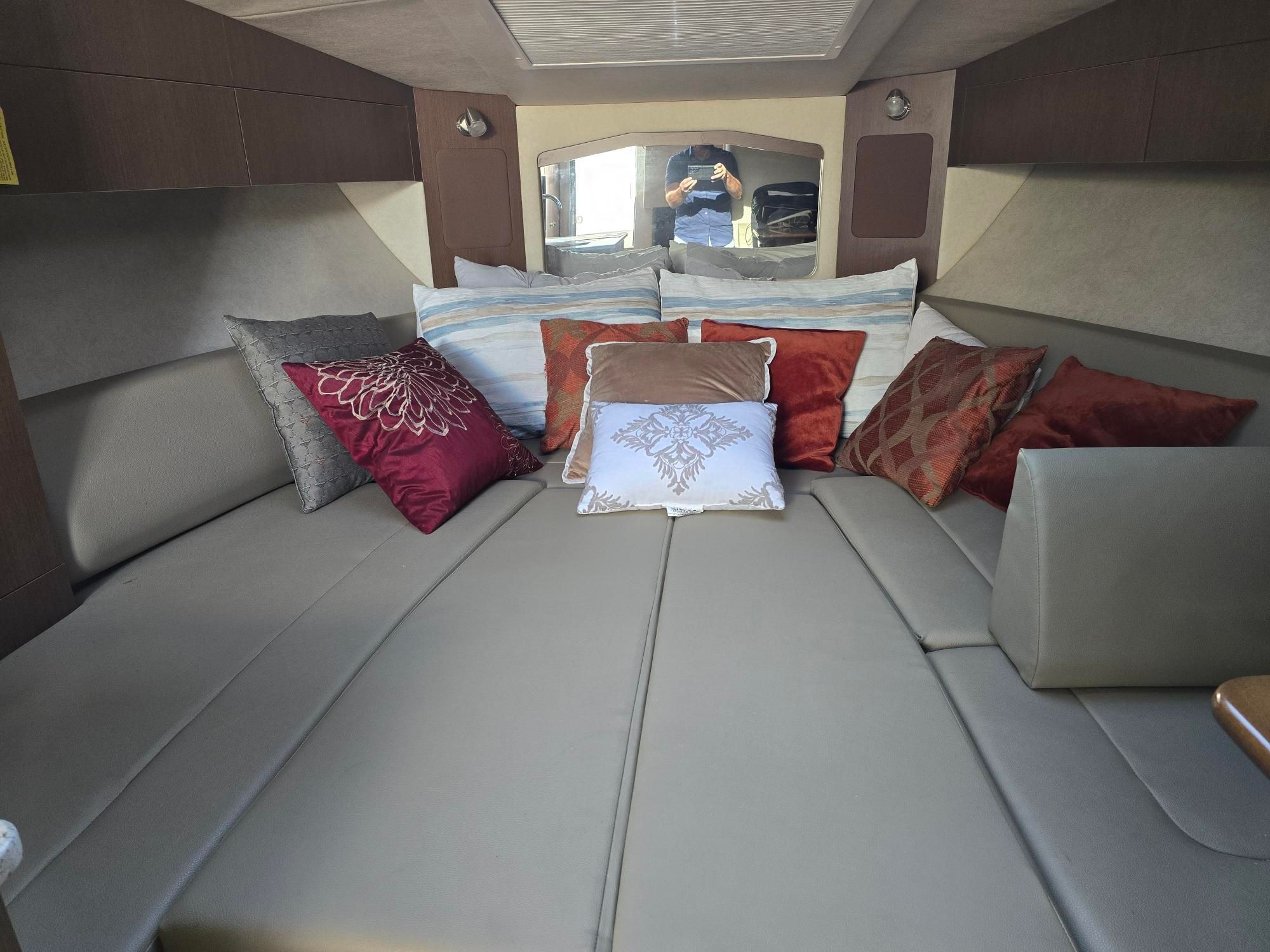 Interior of a Sea Ray Sundancer 310 with cozy pillows on a large bed.