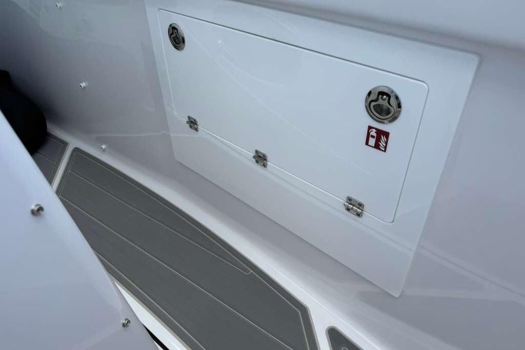 Storage compartment on 2026 Monterey Elite 30 OB boat with safety label.