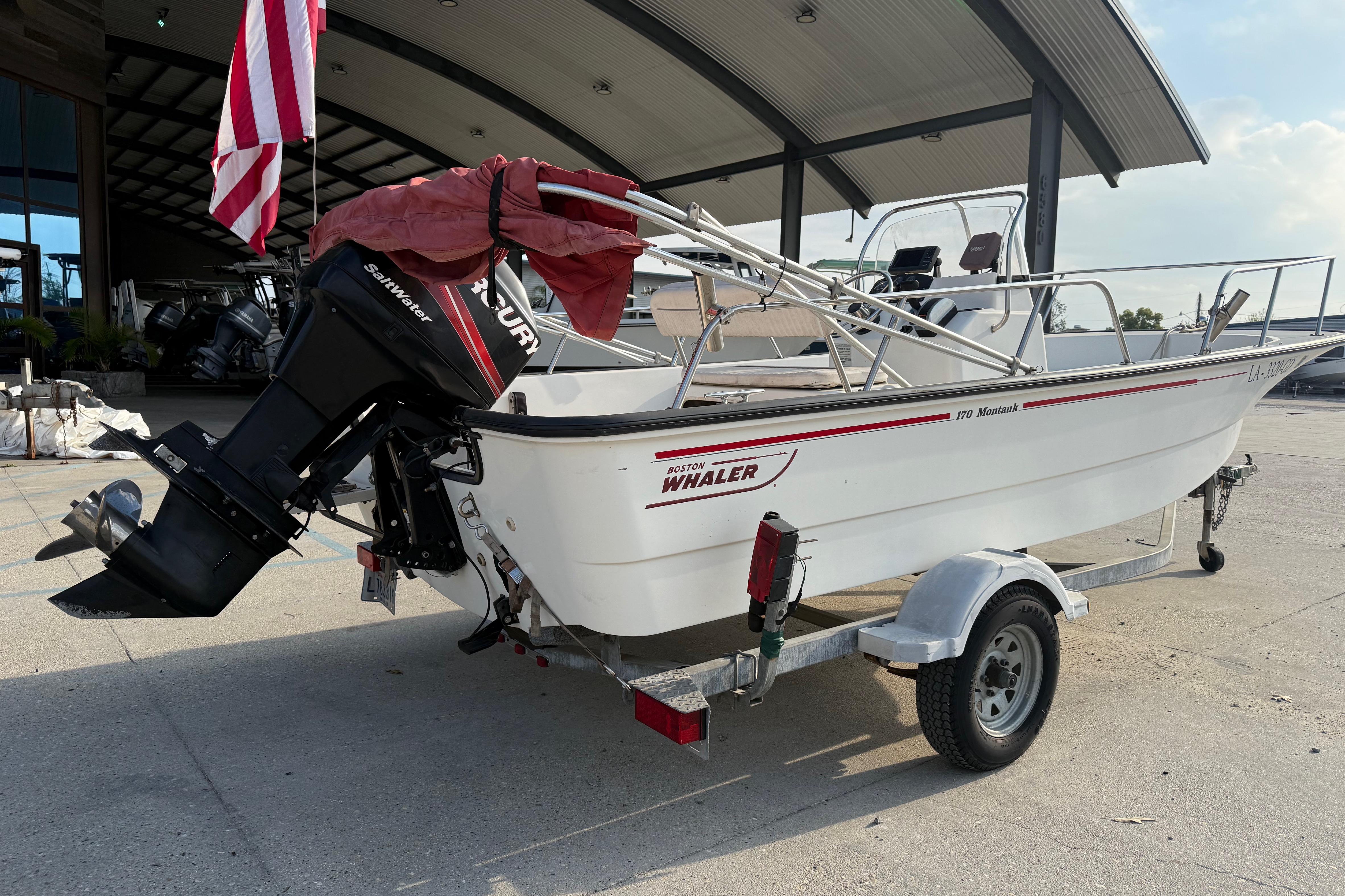 2005 Boston Whaler 17 Montauk boat on trailer, parked outdoors with American flag.