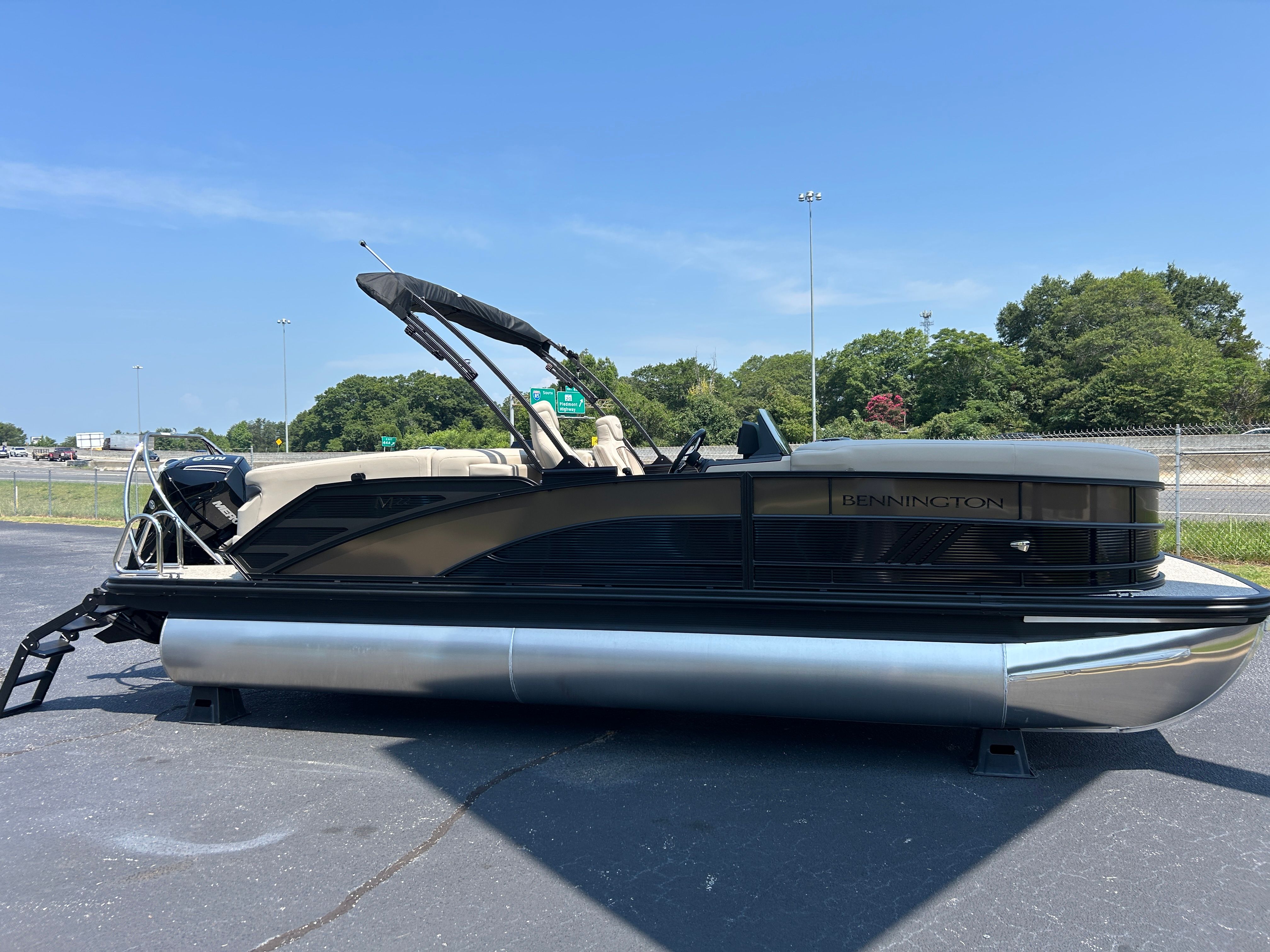 A Bennington 22 MFB pontoon boat is parked on a lot. It features a black canopy and silver pontoons.