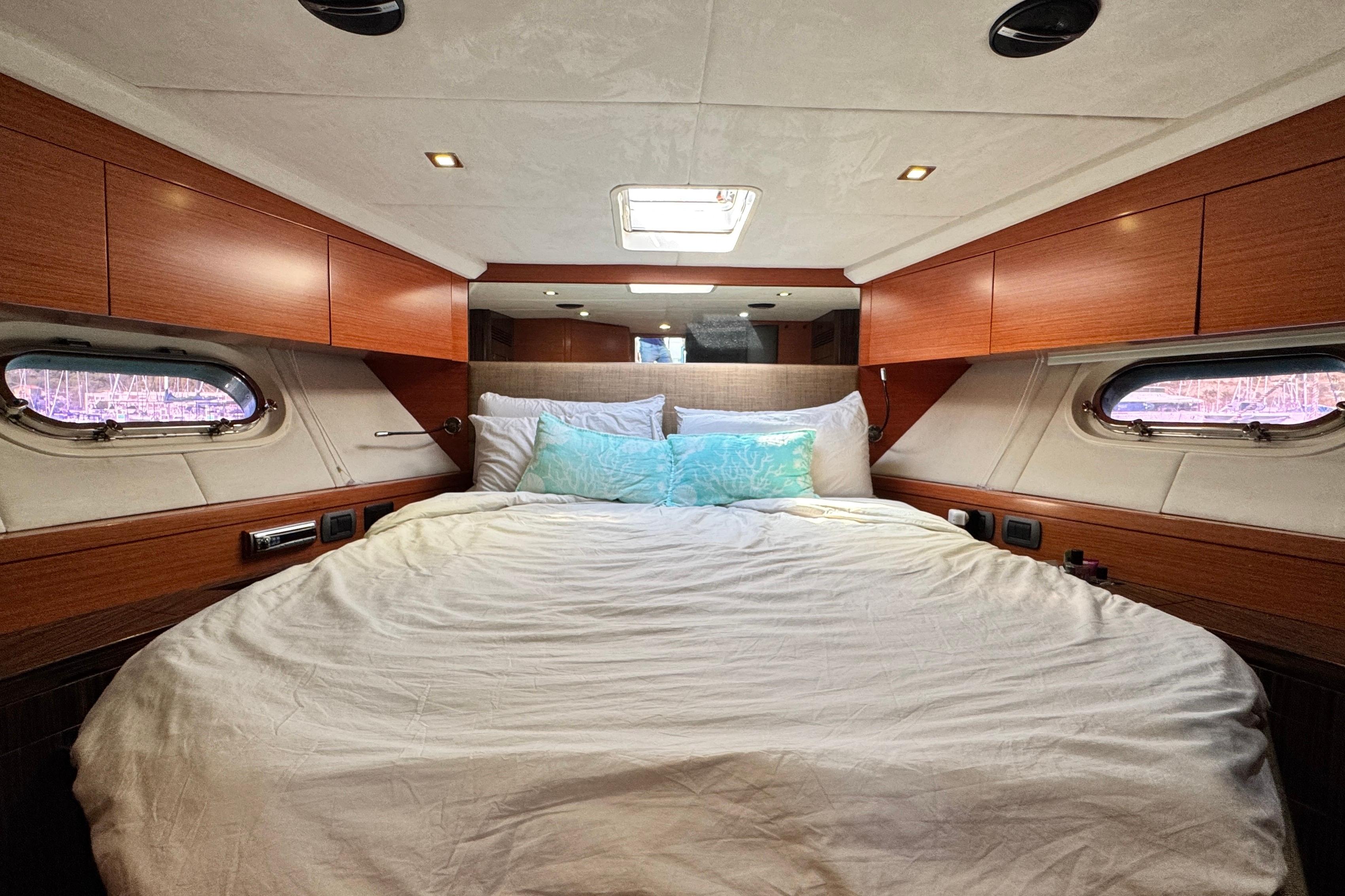 Luxurious cabin interior of 2007 Doma 5 yacht with cozy bed and wooden accents.