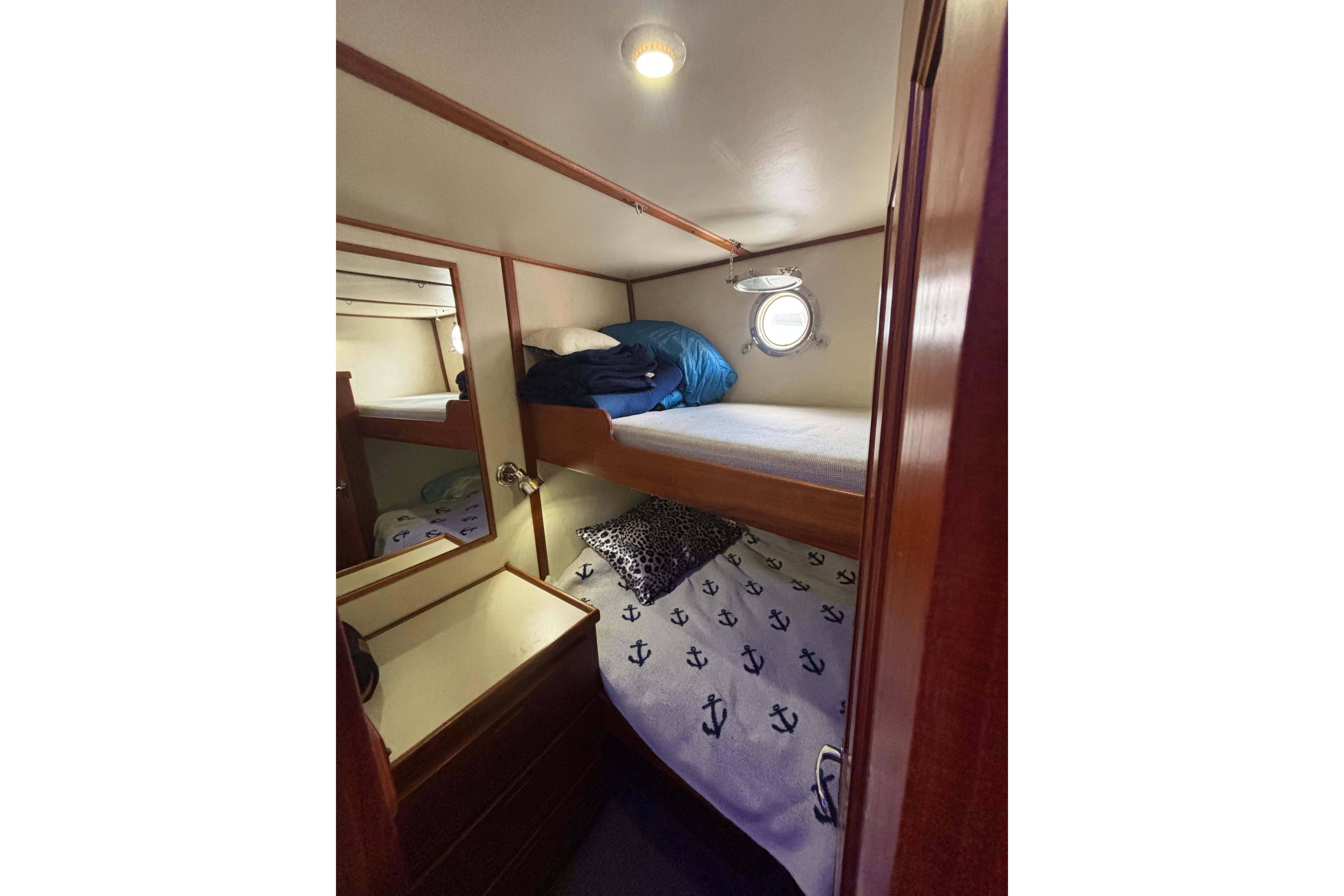 Cozy cabin with bunk beds in 2004 Nordic Tug 37, featuring nautical-themed bedding.