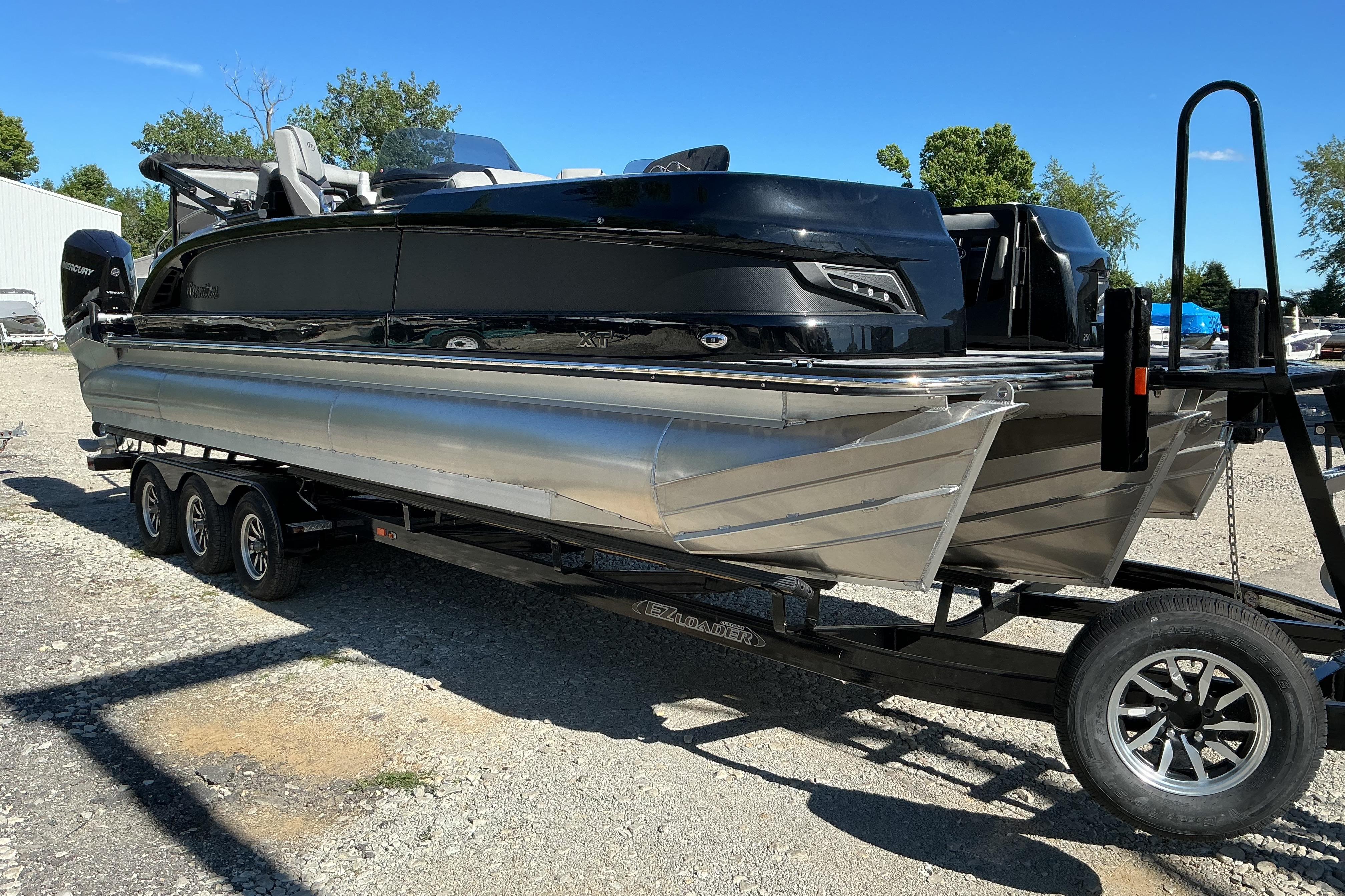 2024 Manitou 25 X-Plode XT SRS pontoon boat on trailer, sunny day.