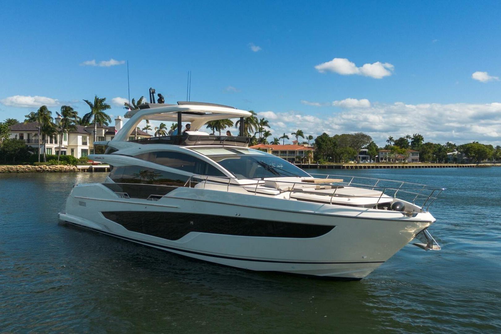 Luxurious 2023 Pearl 72 yacht cruising on a sunny day near waterfront homes.