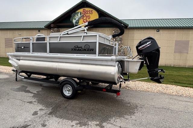 2026 Sun Tracker Bass Buggy 16 XL Select pontoon boat on trailer, outside Bass Pro Shop.