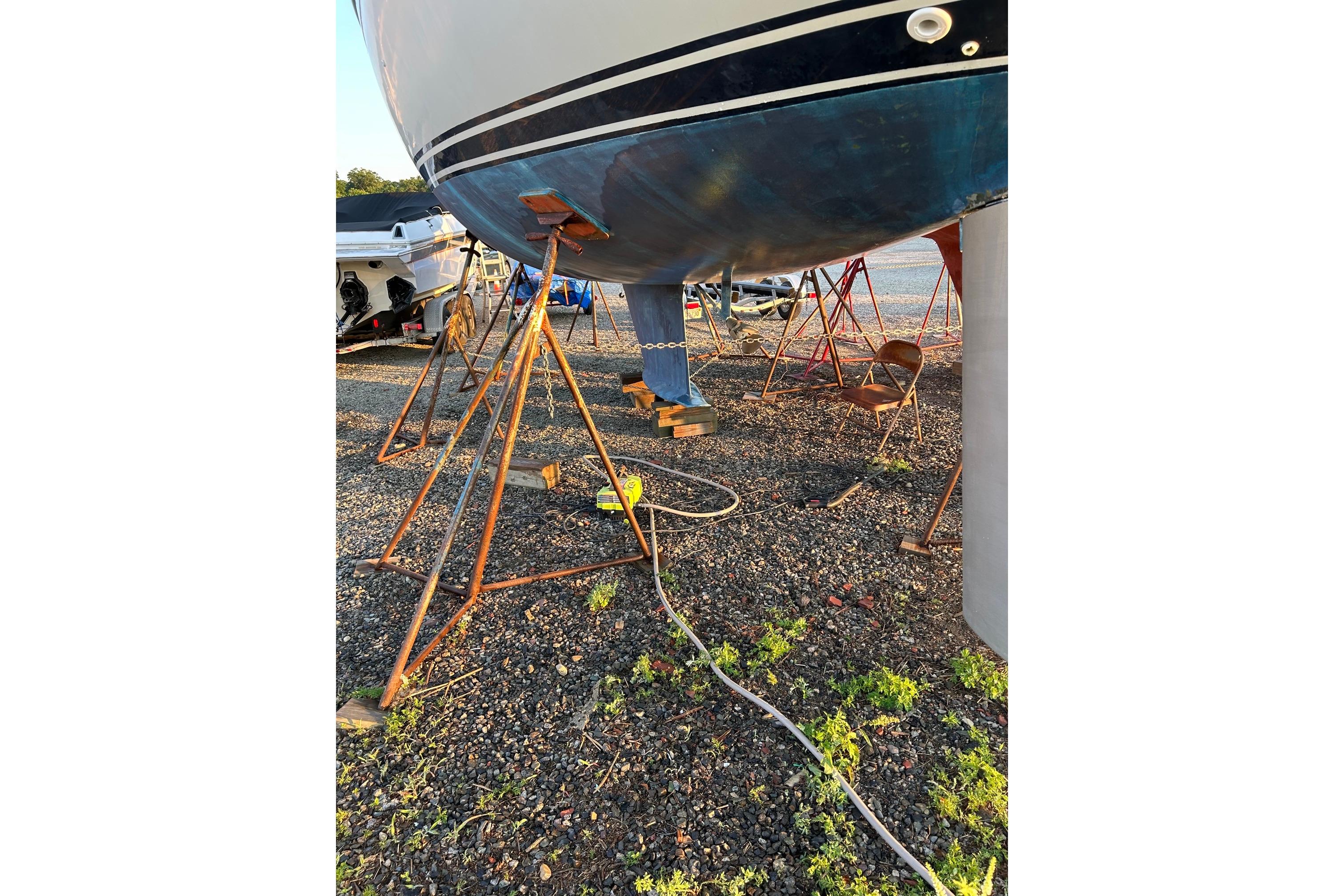 1987 Ericson 38-200 sailboat on stands, gravel ground, sunny day.