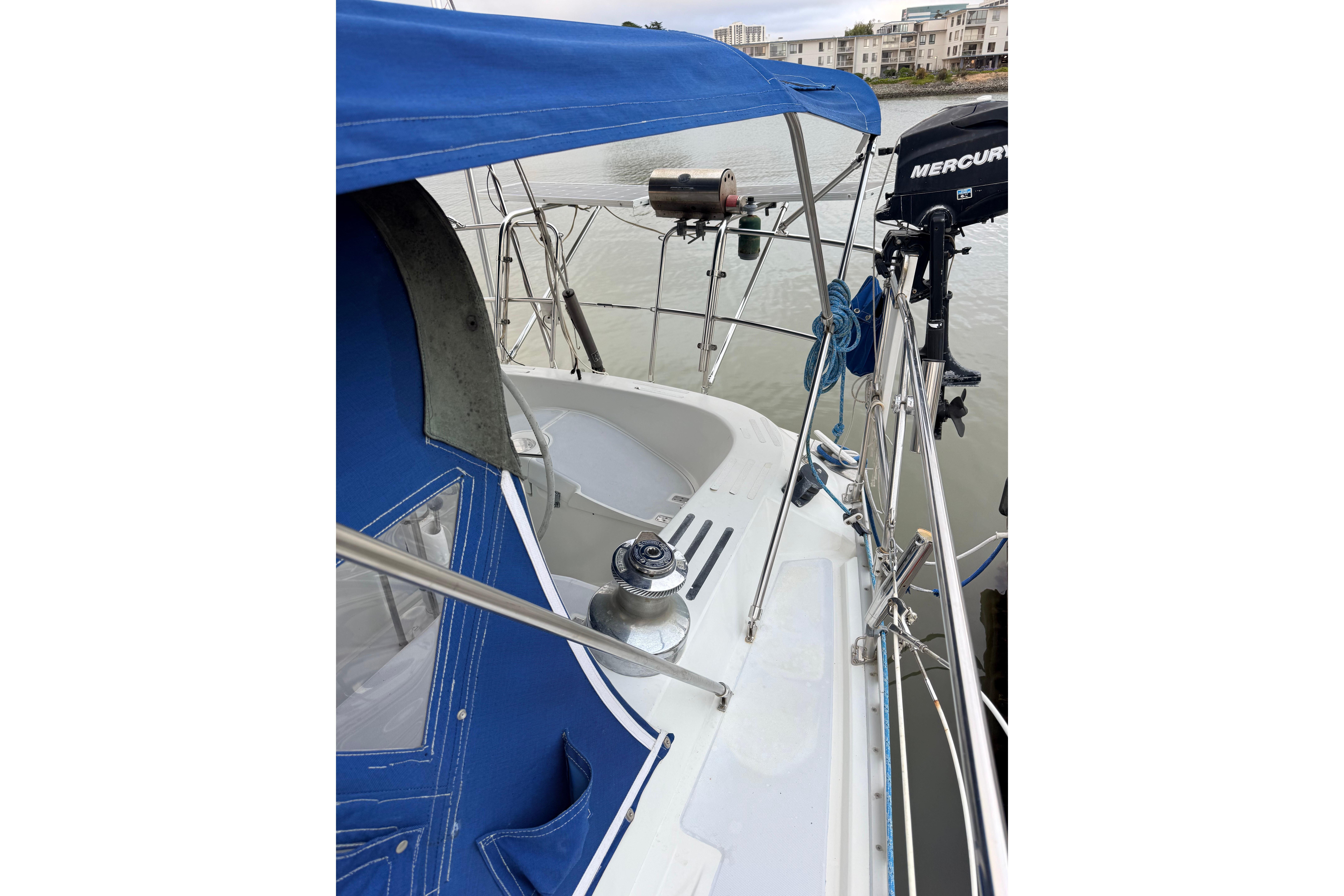 1987 Norseman 400 sailboat with blue canopy and Mercury outboard motor.