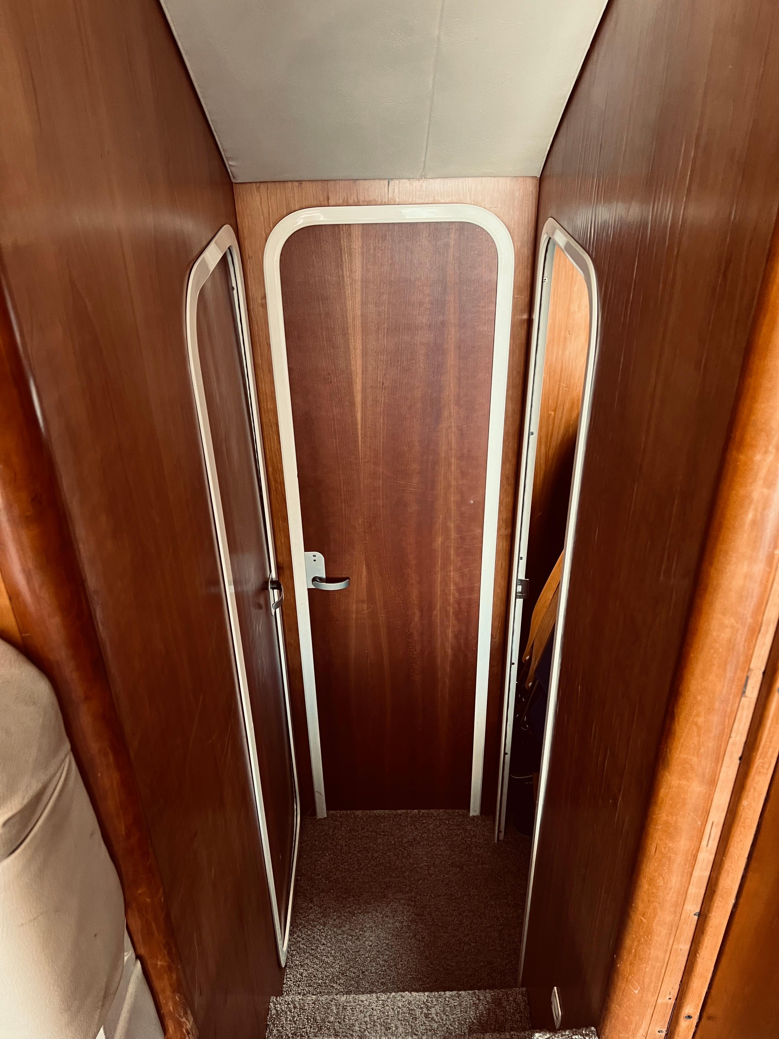 Interior hallway of a 1999 Luhrs 360 Sportfish boat with wooden door.