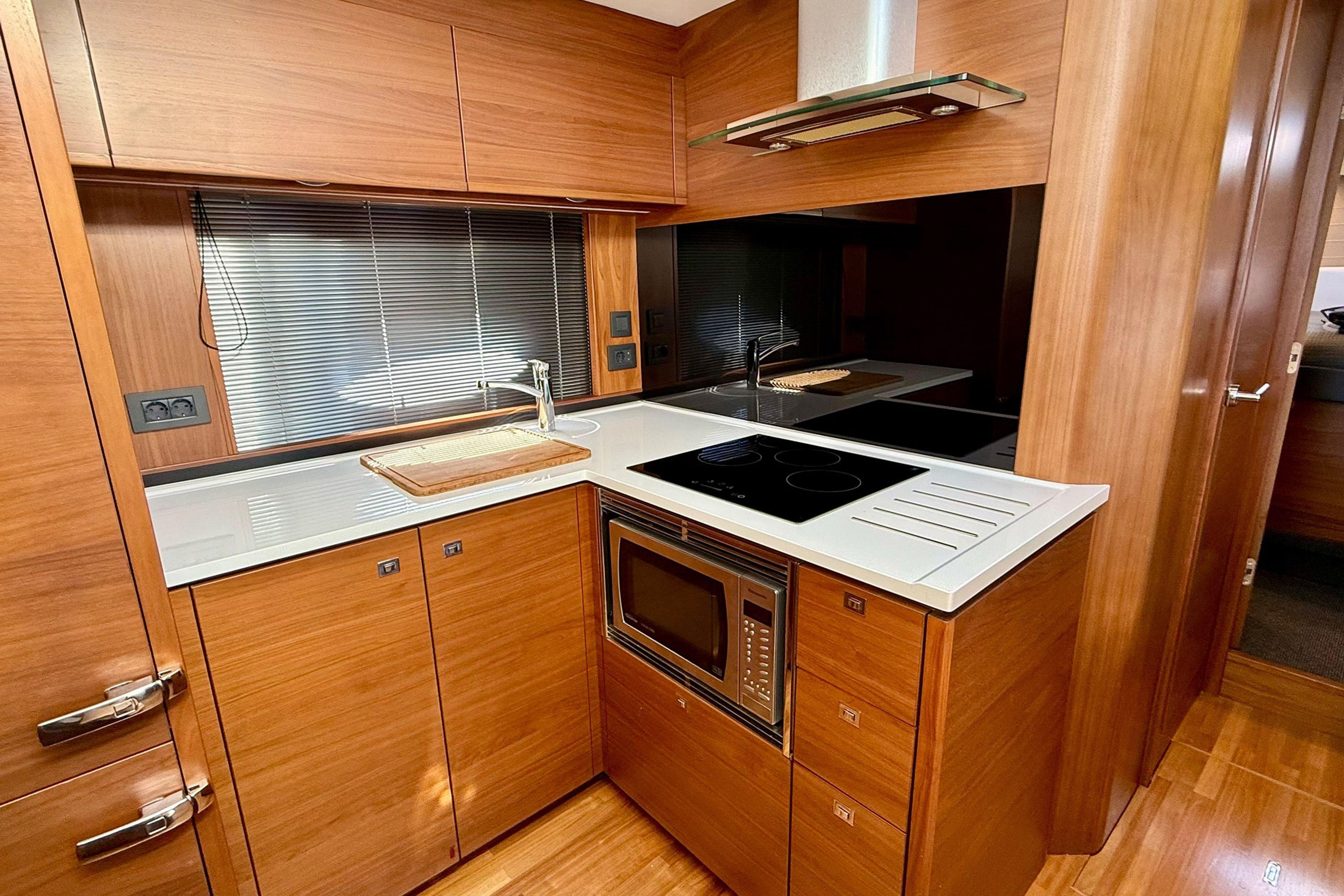Luxurious 2015 Princess V48 yacht kitchen with modern appliances and sleek wood cabinetry.