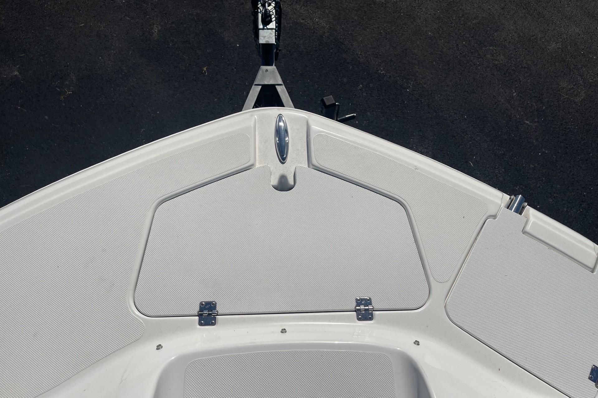 2023 Hurricane SunDeck 2400 OB boat deck with storage compartment and sleek design.