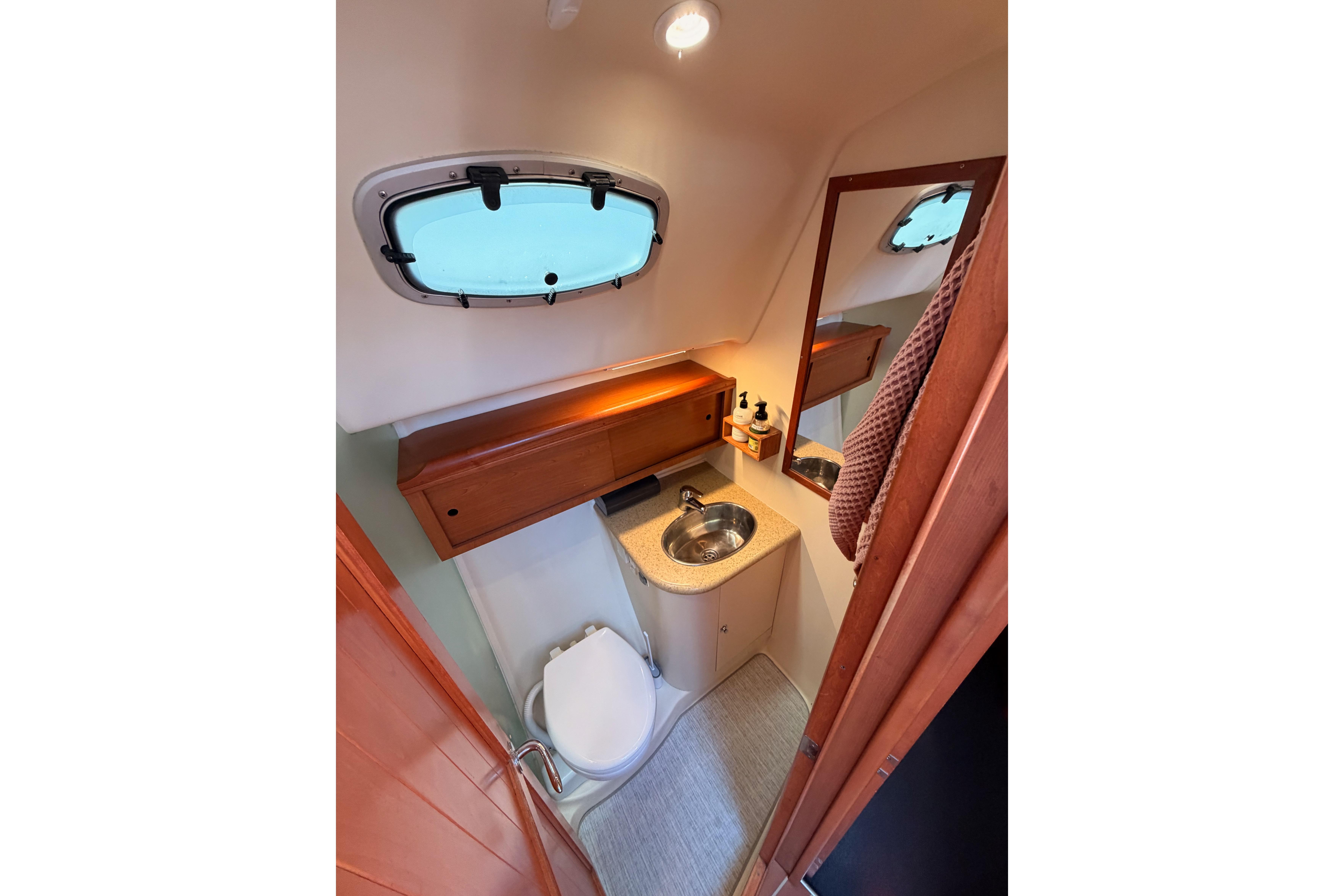 Compact bathroom in 2008 Hunter 45 Deck Salon yacht with sink, toilet, and window.