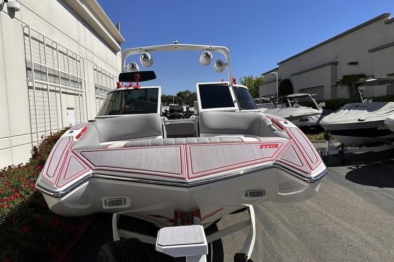 2023 MB SPORTS F22 Tomcat Alpha boat, sleek design, parked outdoors under clear blue sky.
