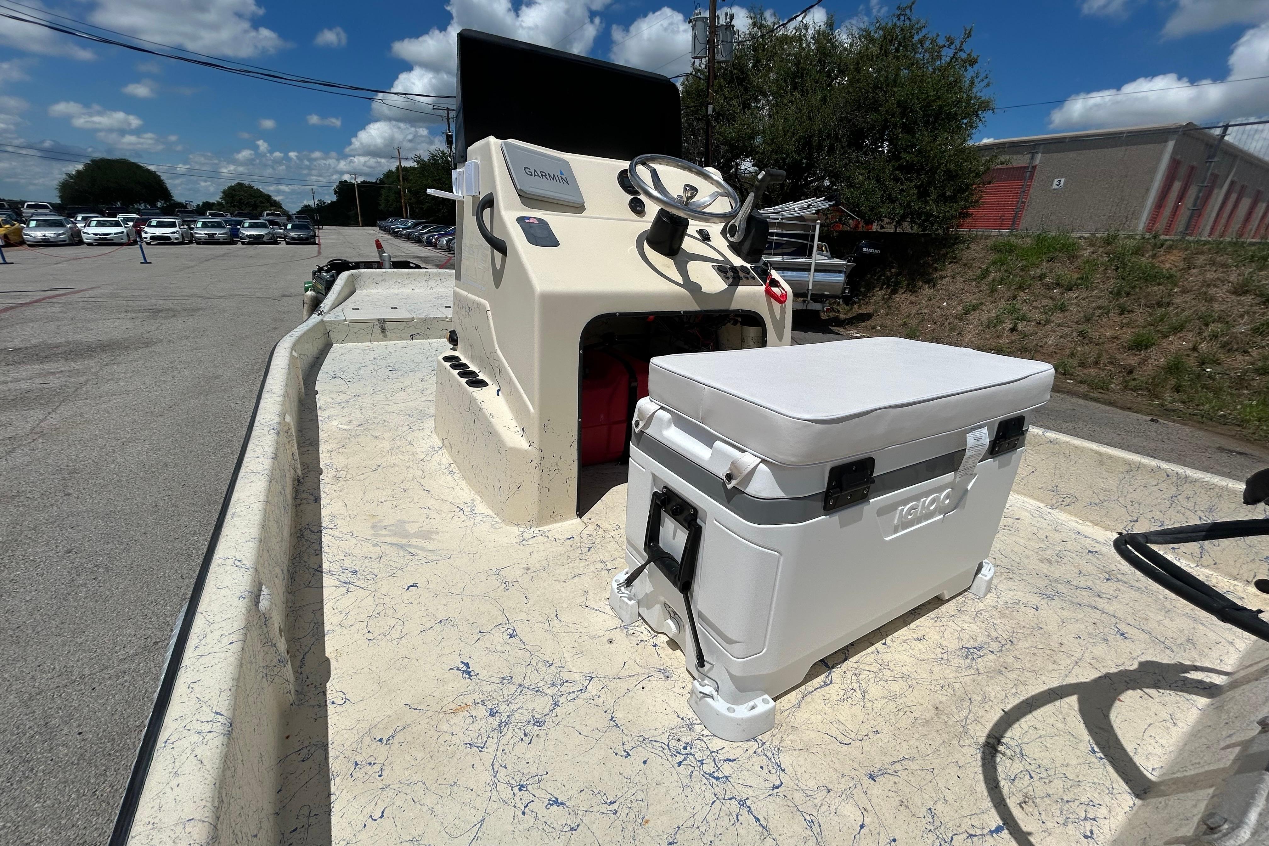 2007 Flats Cat 19 boat interior with steering console and Igloo cooler under blue sky.