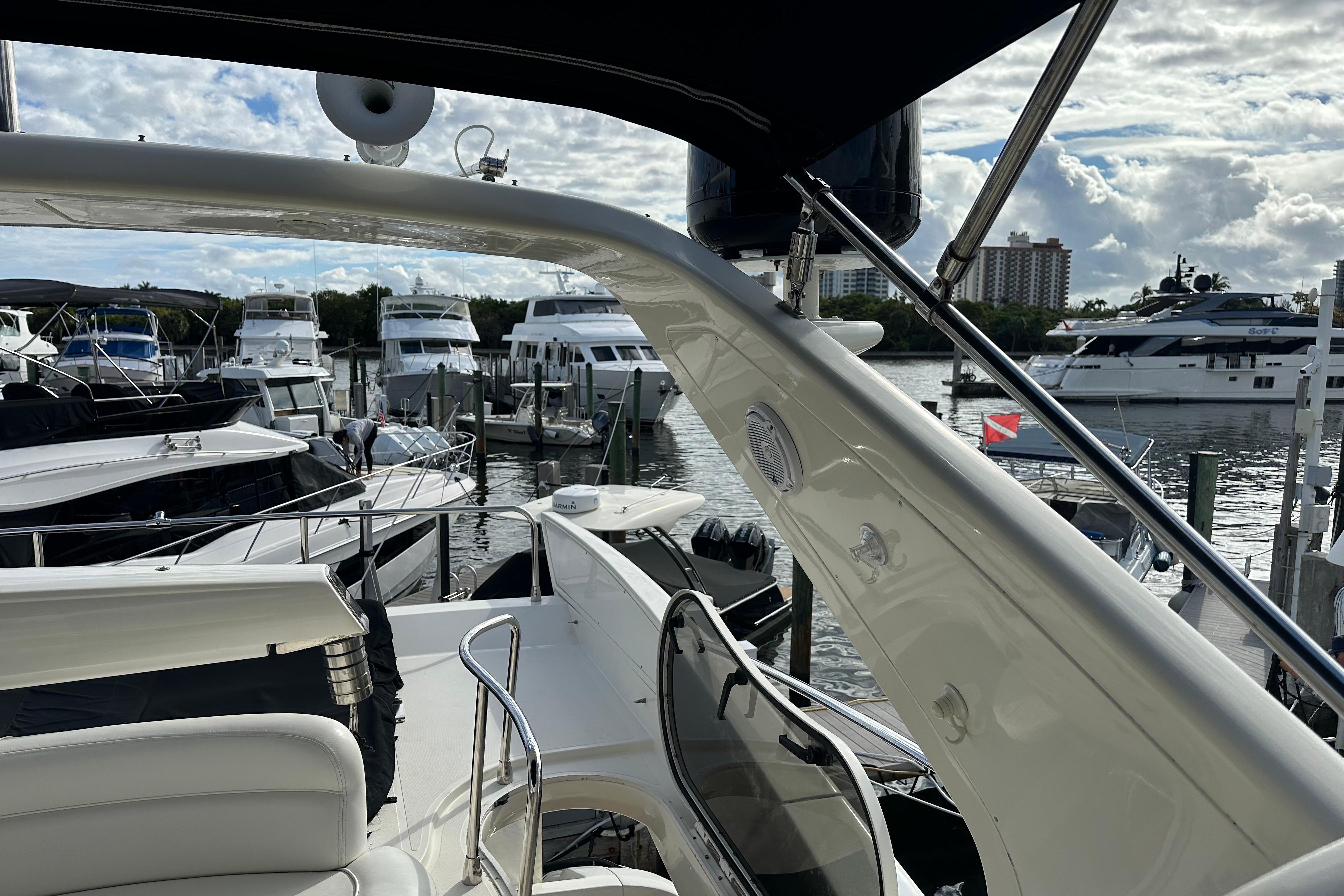 2004 Azimut 55E yacht docked at marina with other boats under cloudy sky.