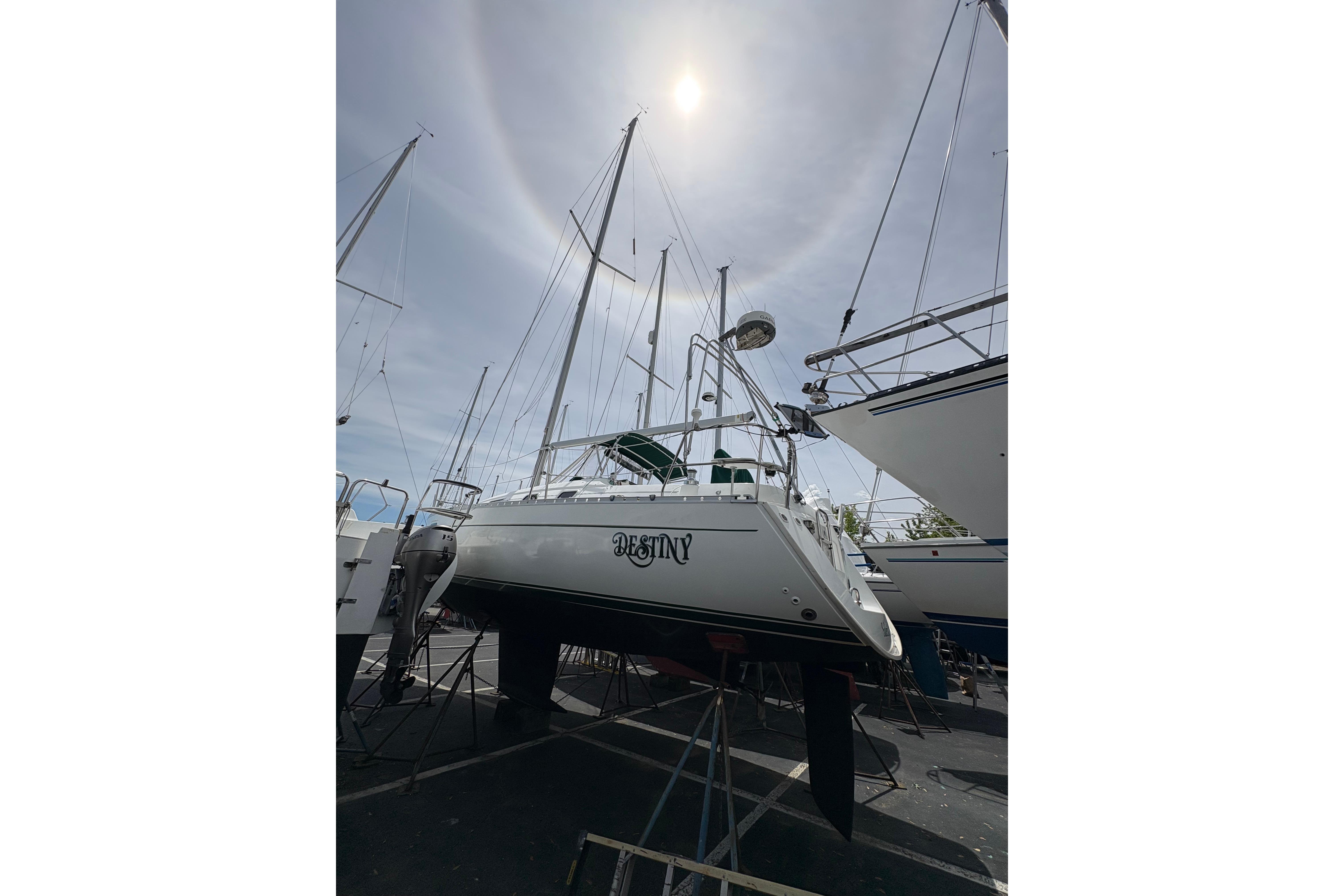 Beneteau Oceanis 321 sailboat from 2000 on dry dock under a bright sky.