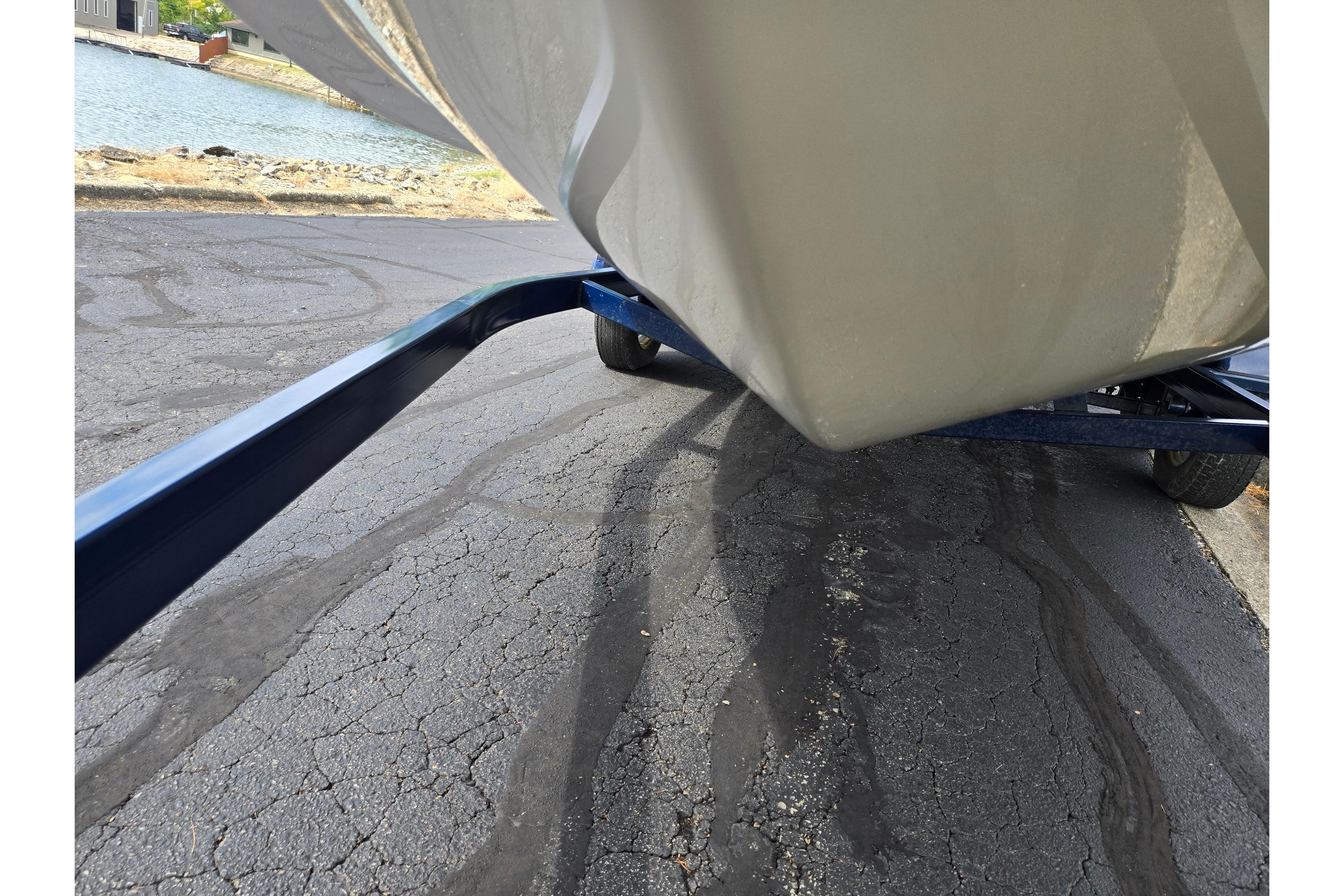 2001 Glastron GX 205 boat on trailer near water, asphalt surface visible.