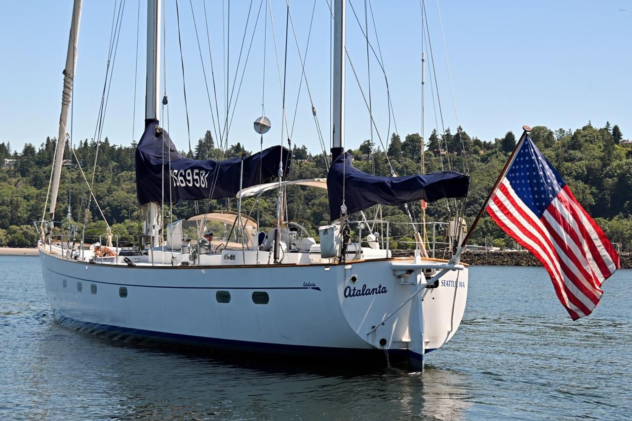 Sailing yacht "Atalanta" by Abeking & Rasmussen Tripp, 1968, with American flag, on serene water.