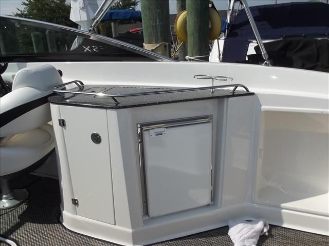 A sleek boat with a small kitchenette and refrigerator on board.