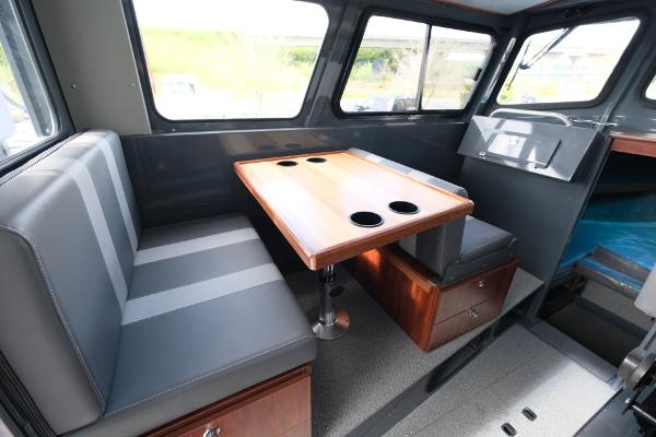 Interior of 2024 Hewescraft 250 Explorer, featuring a dining area with cushioned seating and table.