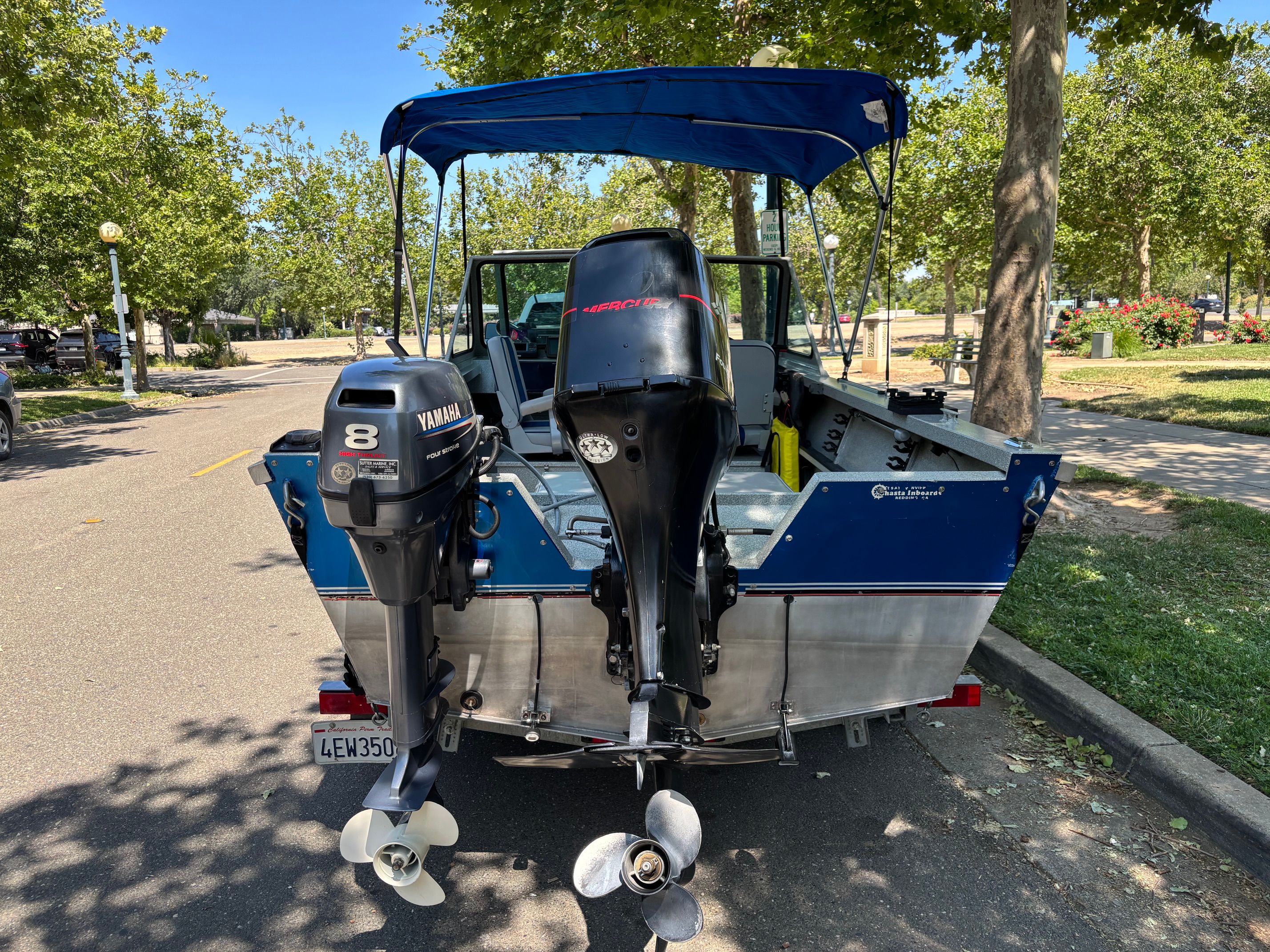 A 2002 Stryker Rogue boat with two outboard motors, parked in a sunny parking area.