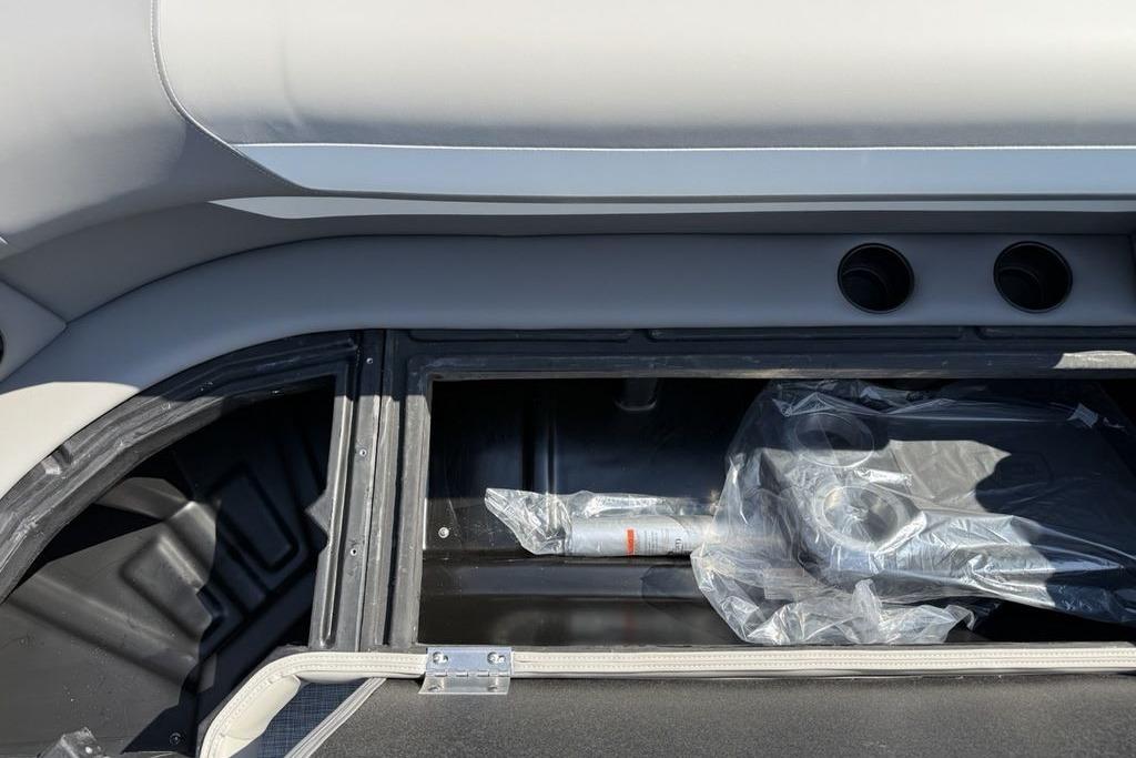 Storage compartment of 2026 Premier 220 Sunscape RF boat, featuring cup holders and accessories.
