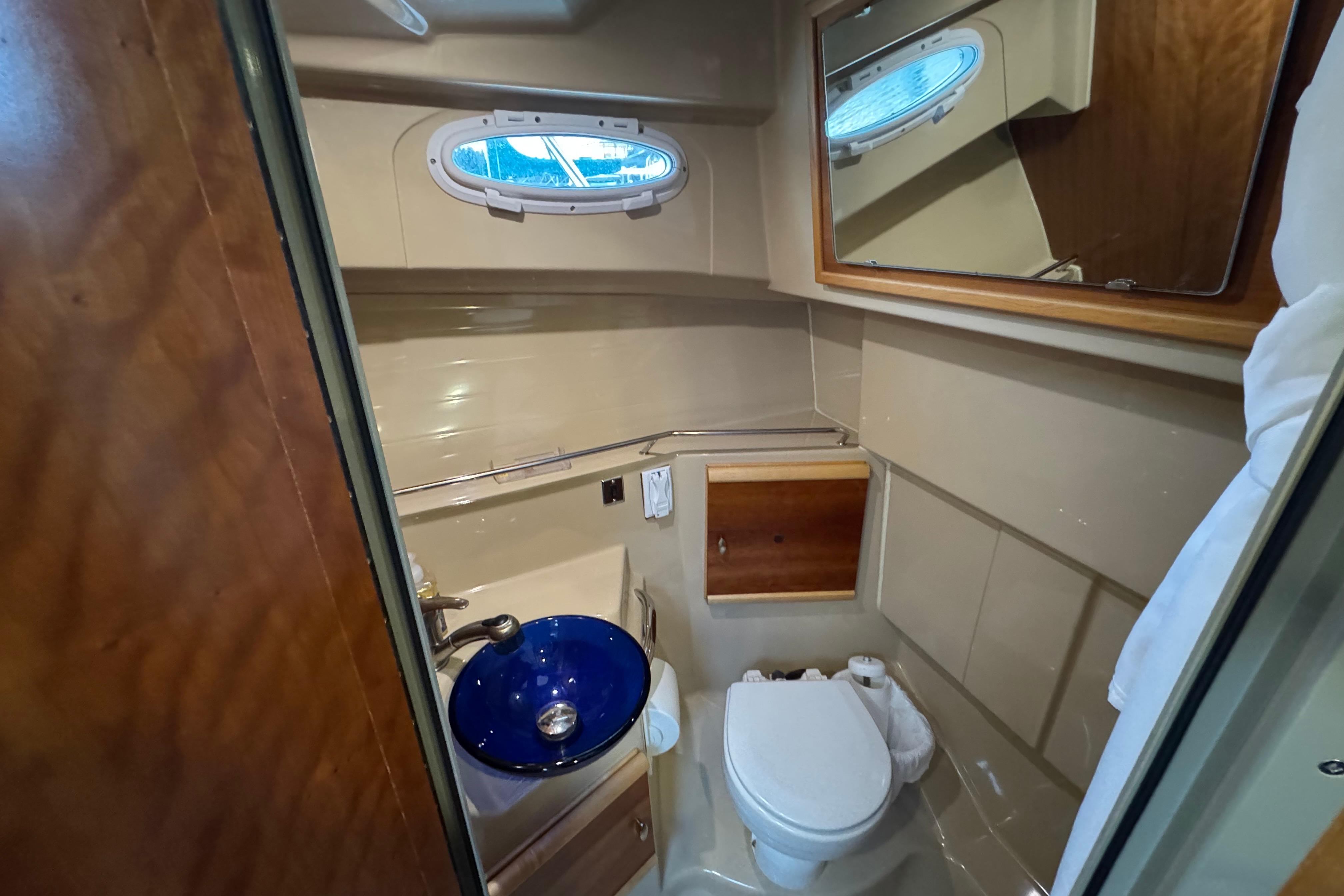 2014 Cutwater 28 boat bathroom with blue sink, toilet, and mirror.