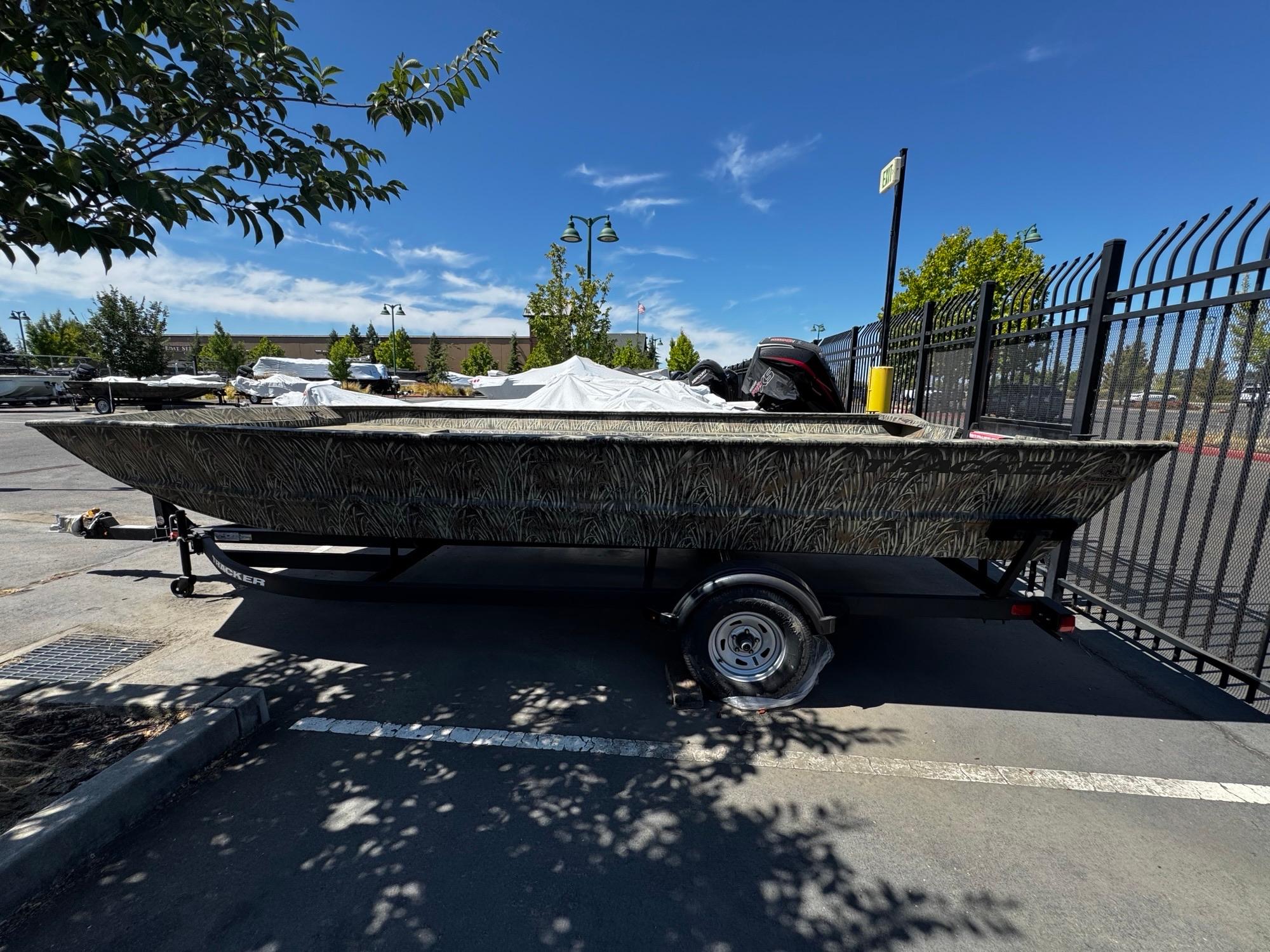 2025 Tracker GRIZZLY 2072 Utility boat on trailer in parking lot, sunny day.