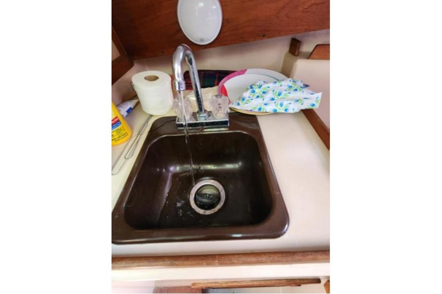 1985 Wasque Down East Cruiser kitchen sink with running water and cleaning supplies.