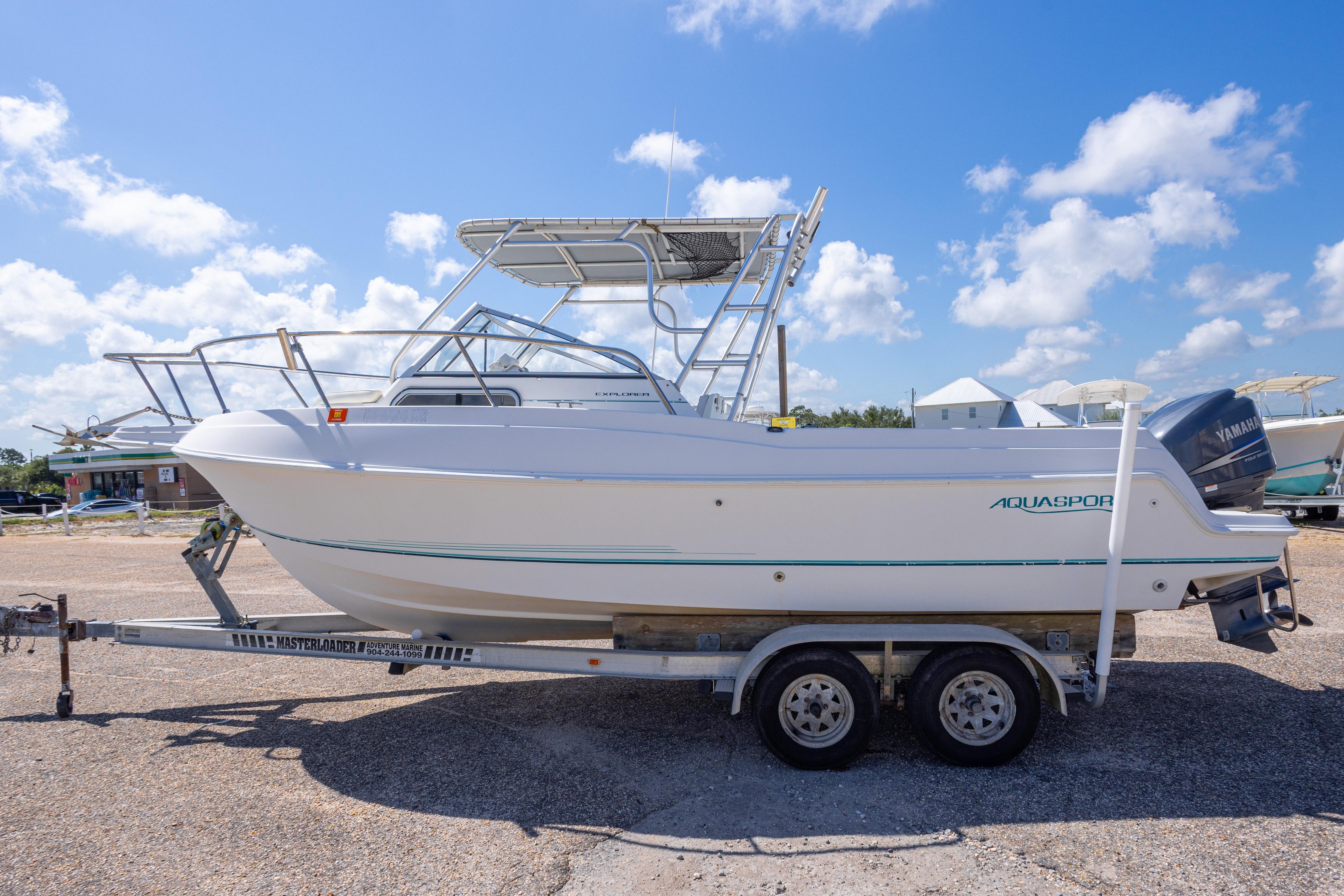 1999 Aquasport 225 Explorer boat on trailer under blue sky.
