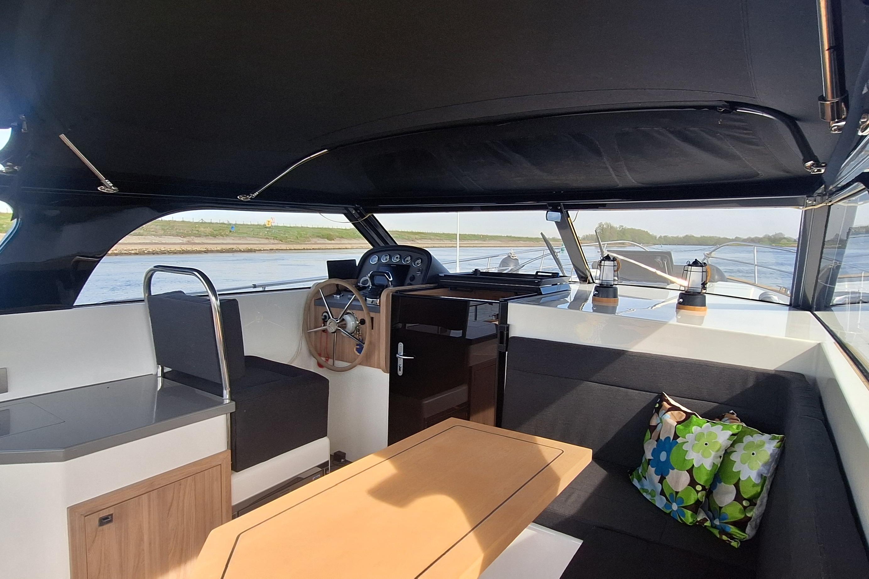 Interior of 2023 Antaris X boat with steering wheel, seating, and decorative pillows.