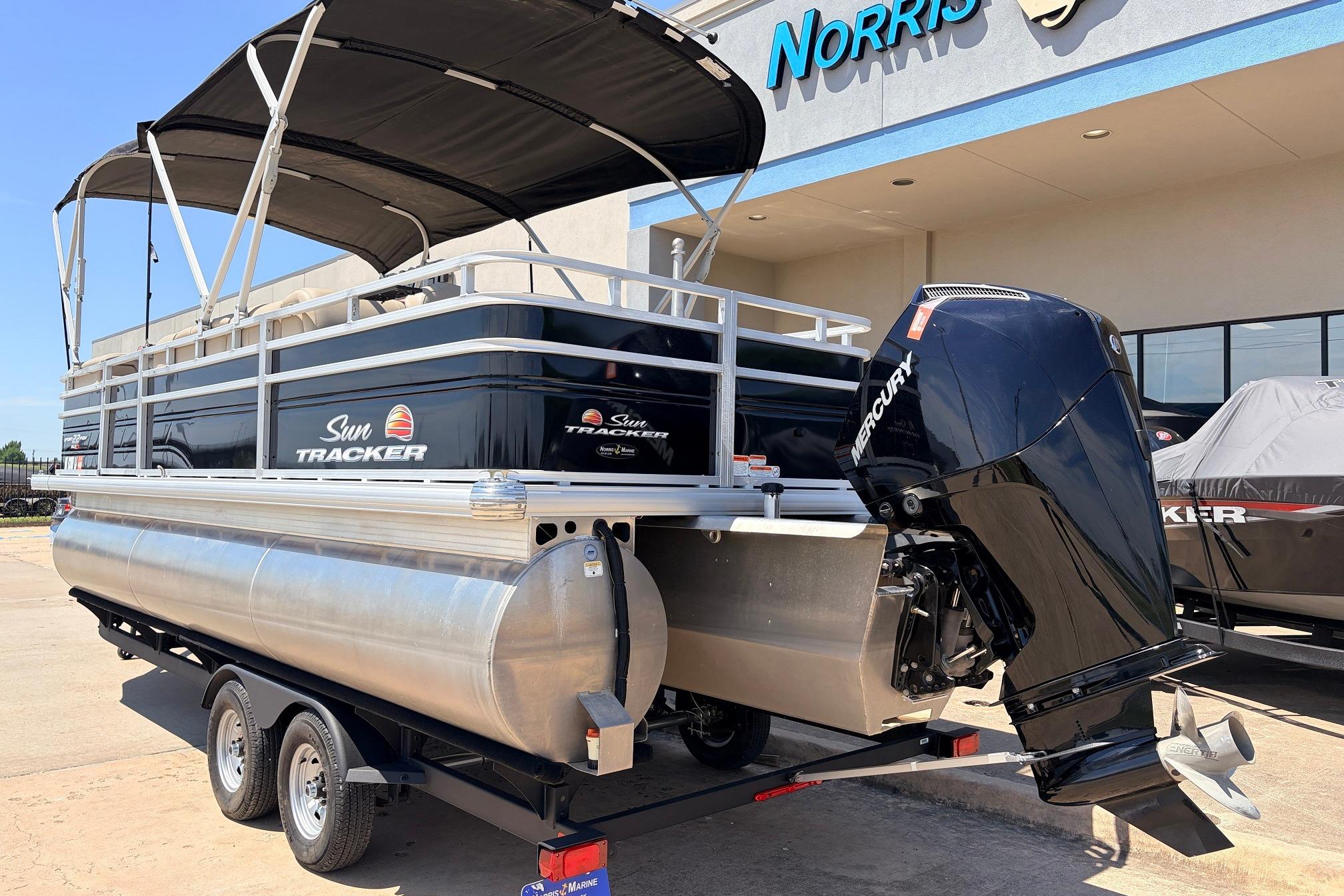 2024 Sun Tracker SportFish 22 XP3 pontoon boat with Mercury outboard motor, parked outside dealership.