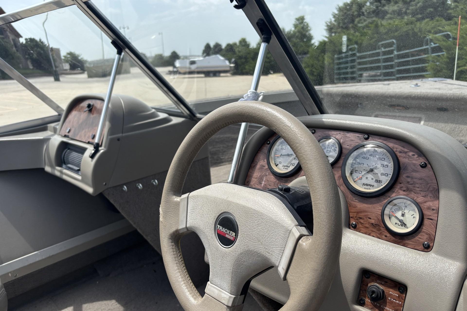 1999 Tracker Targa 18 boat dashboard with steering wheel and gauges in a sunny setting.