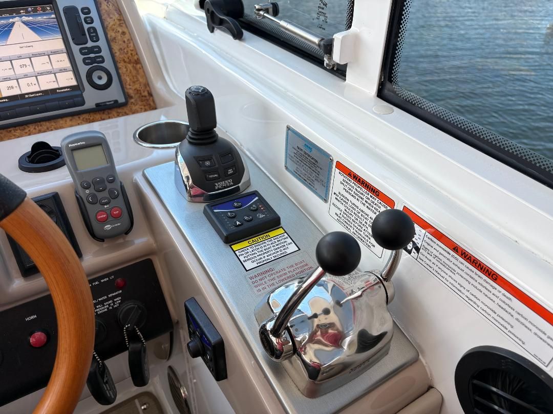 The image shows a boat's helm with various controls and a wooden steering wheel.