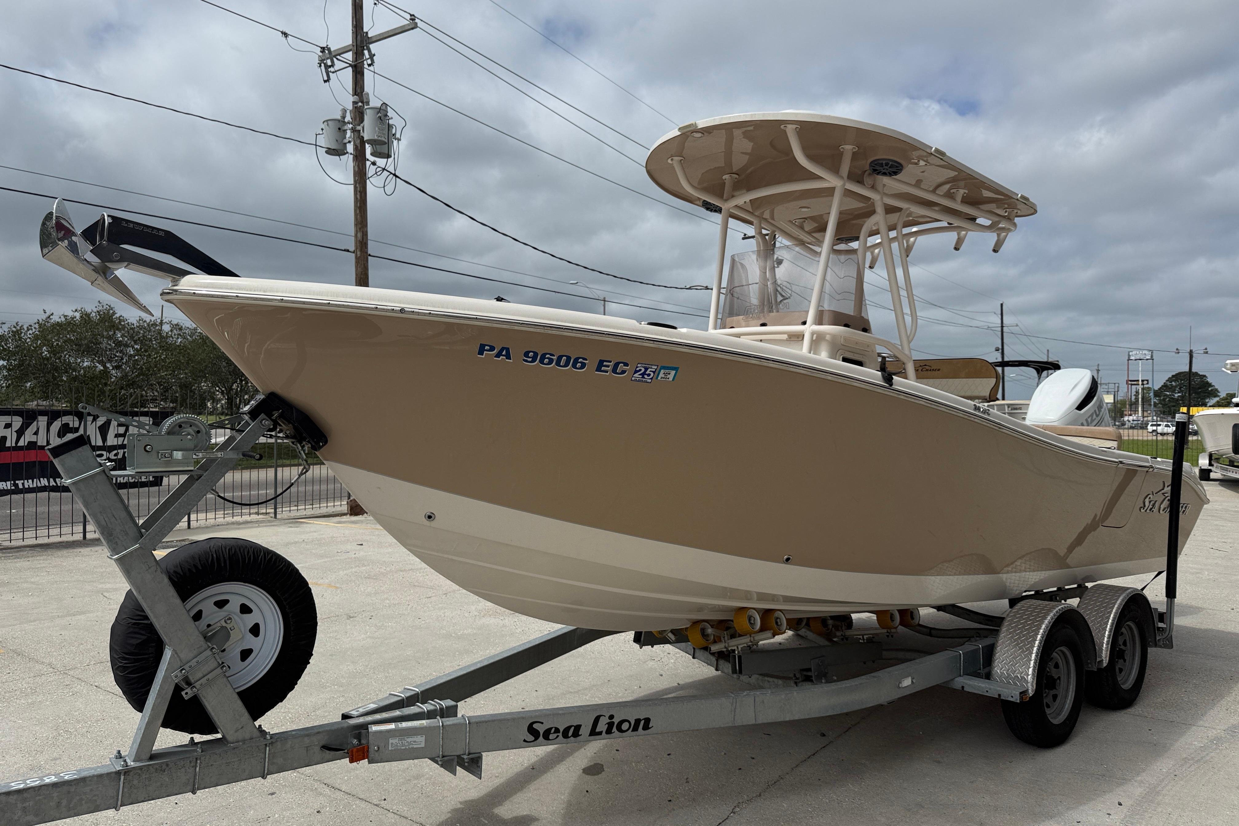 2023 SeaChaser 24 HFC boat on trailer, parked outdoors under cloudy sky.