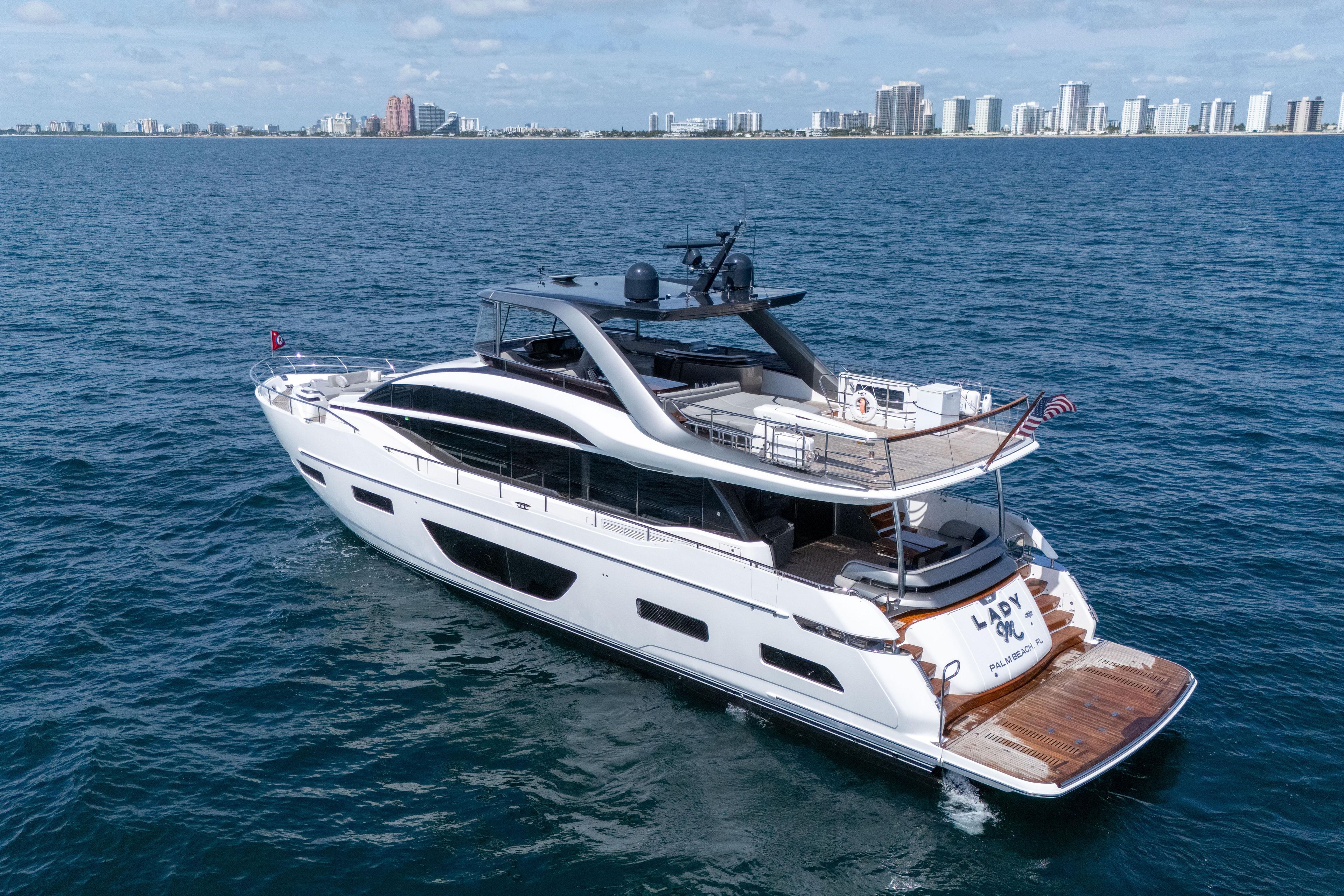Luxurious 2020 Princess Y85 yacht cruising near a city skyline on a sunny day.