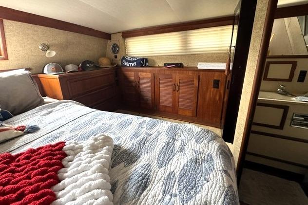 Cozy bedroom interior of 1980 Viking 43 Convertible yacht with wood cabinetry and nautical decor.