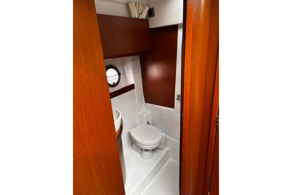 Bathroom interior of 2013 Beneteau Gran Turismo 38 yacht, featuring wooden cabinetry and porthole.