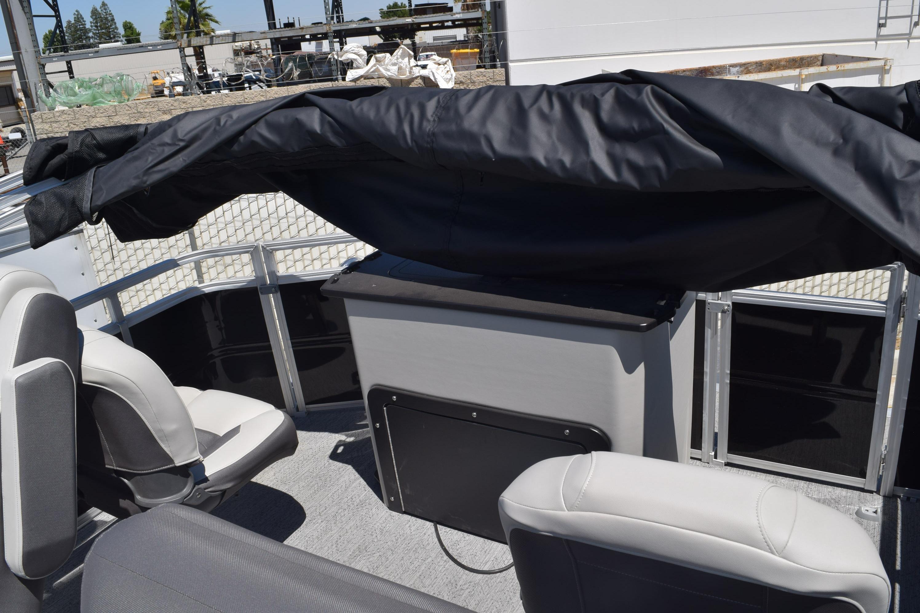 2026 Sun Tracker Fishin' Barge 20 DLX interior with covered seating and storage area.